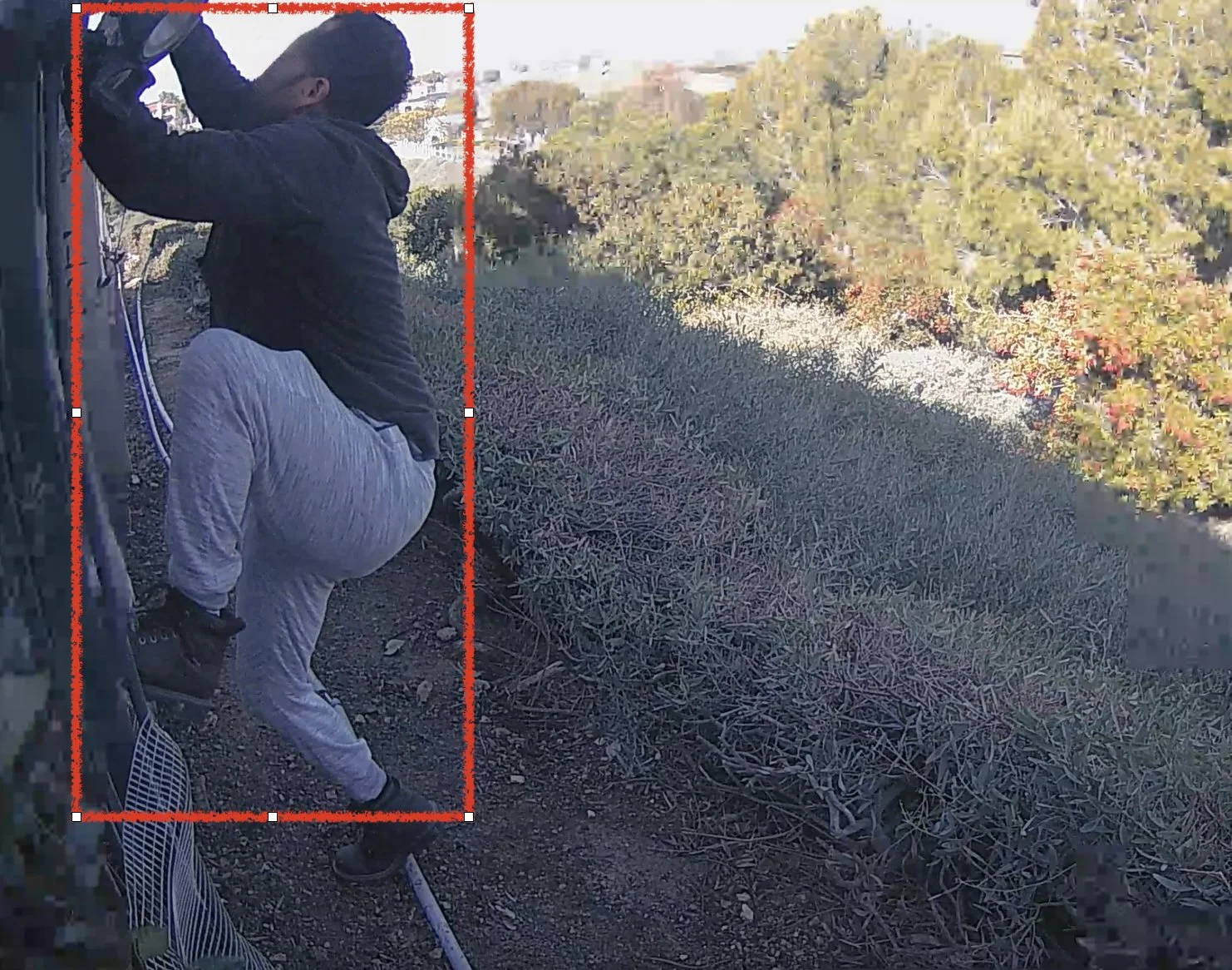 An individual climbing a fence and caught on camera trying to break into a location.