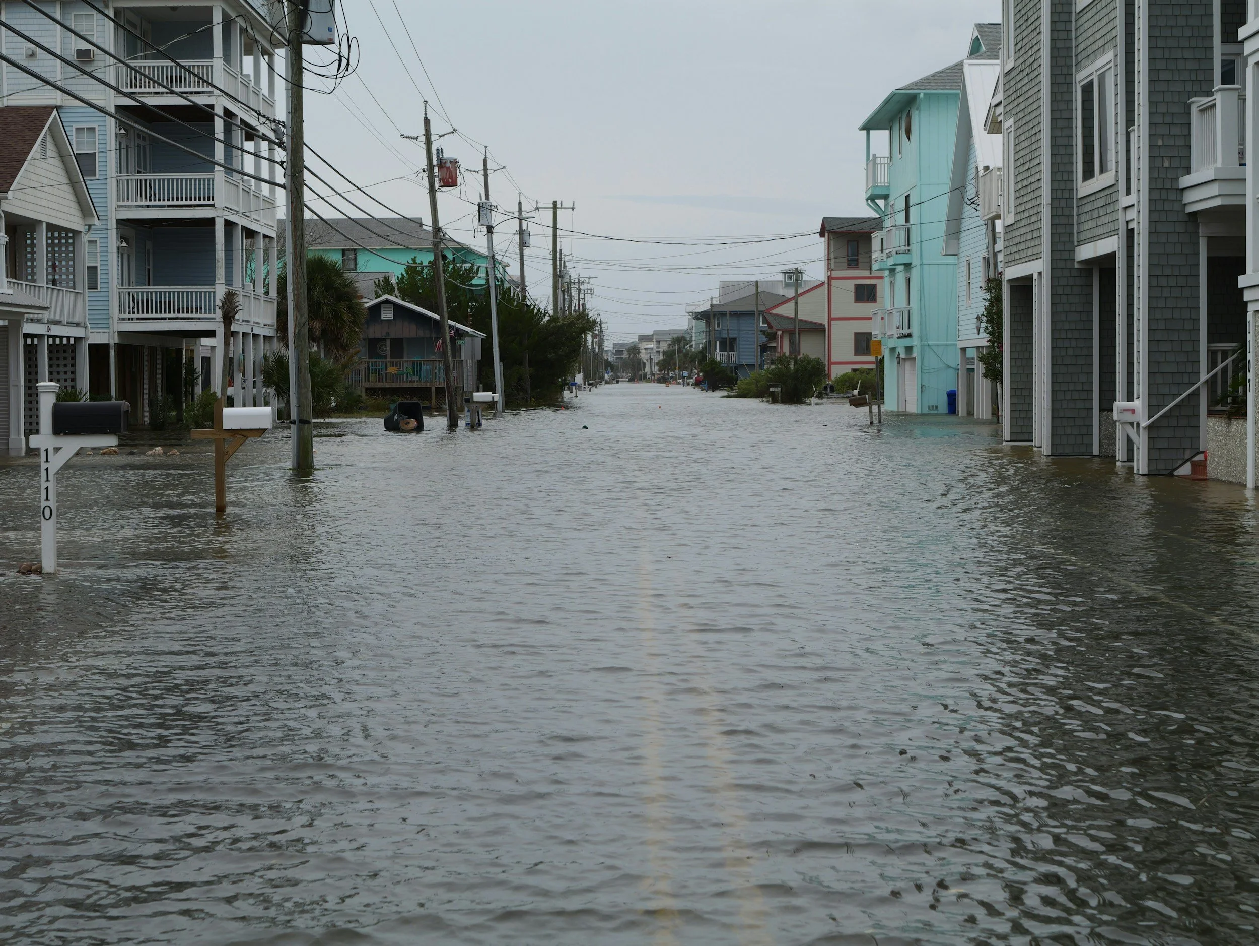 Flooded residential street with water covering the roadway and surrounding houses