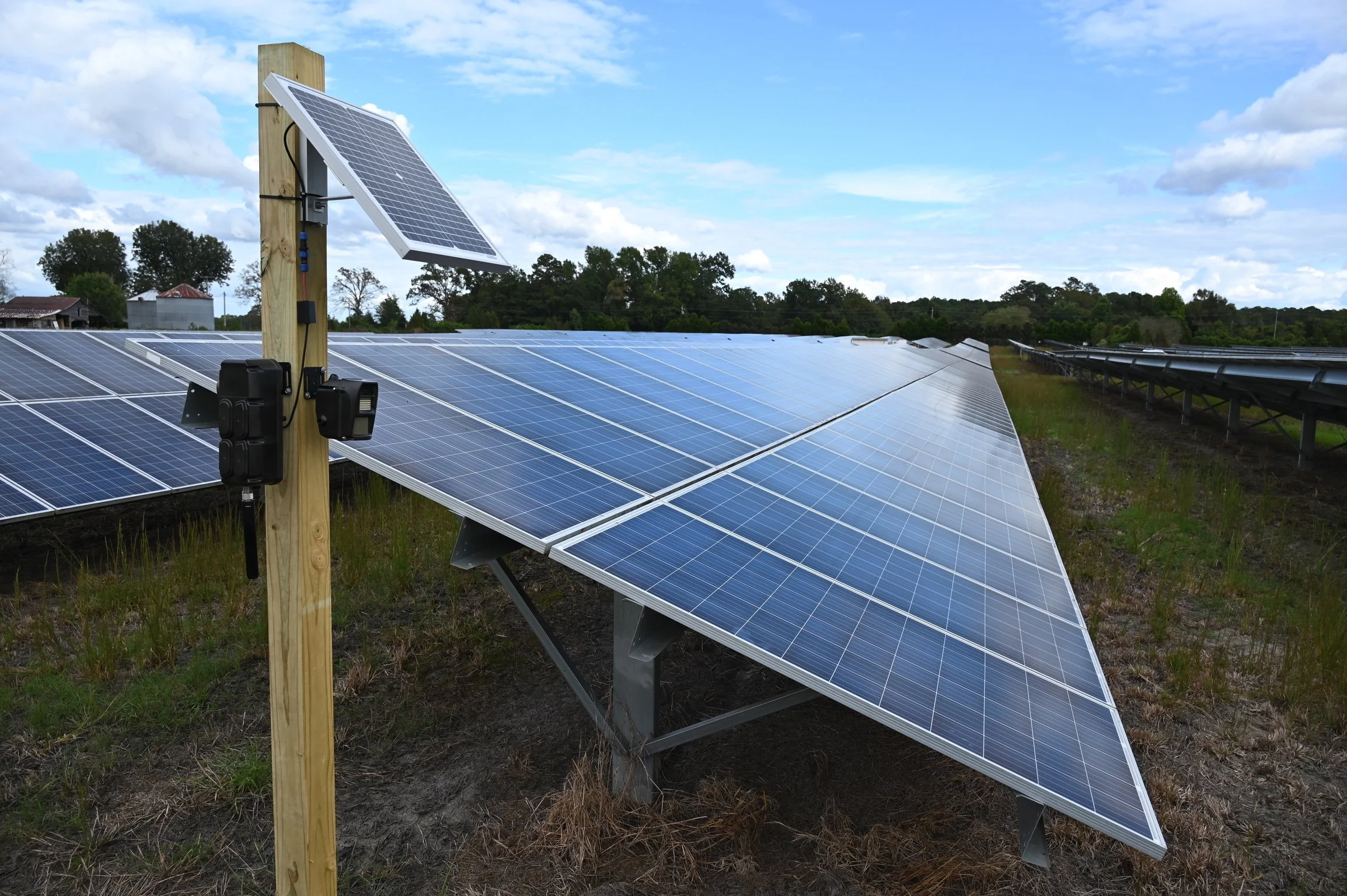 Field of solar panels on metal supports under a partly cloudy sky.