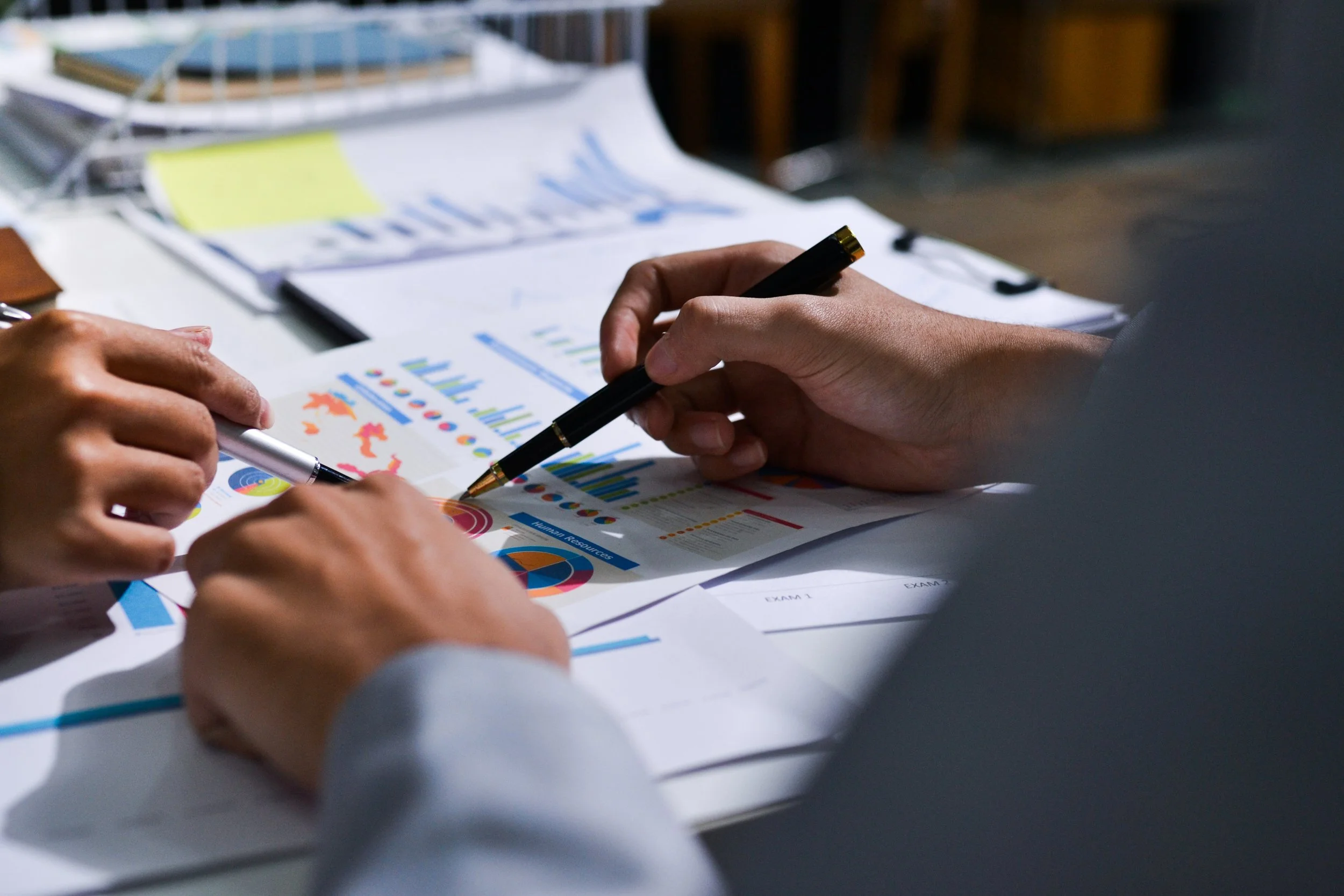 People reviewing colorful charts and graphs on papers during a meeting.