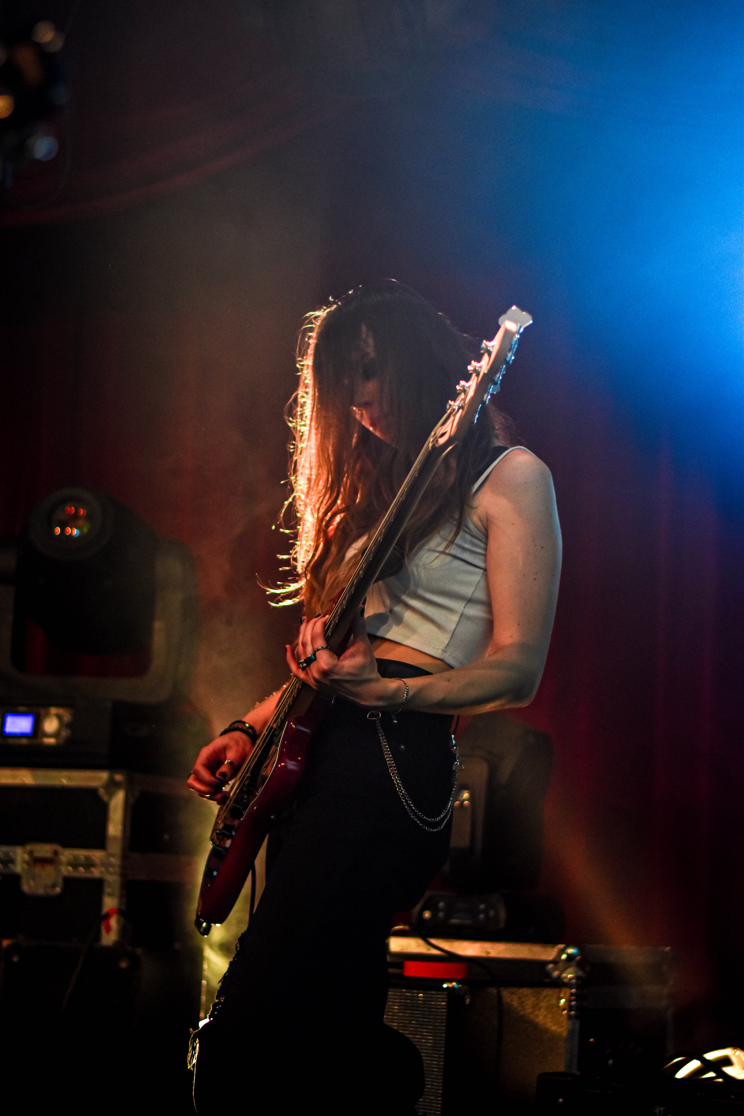 Une jeune femme joue de la guitare électrique dans un studio de musique, éclairée par des lumières colorées