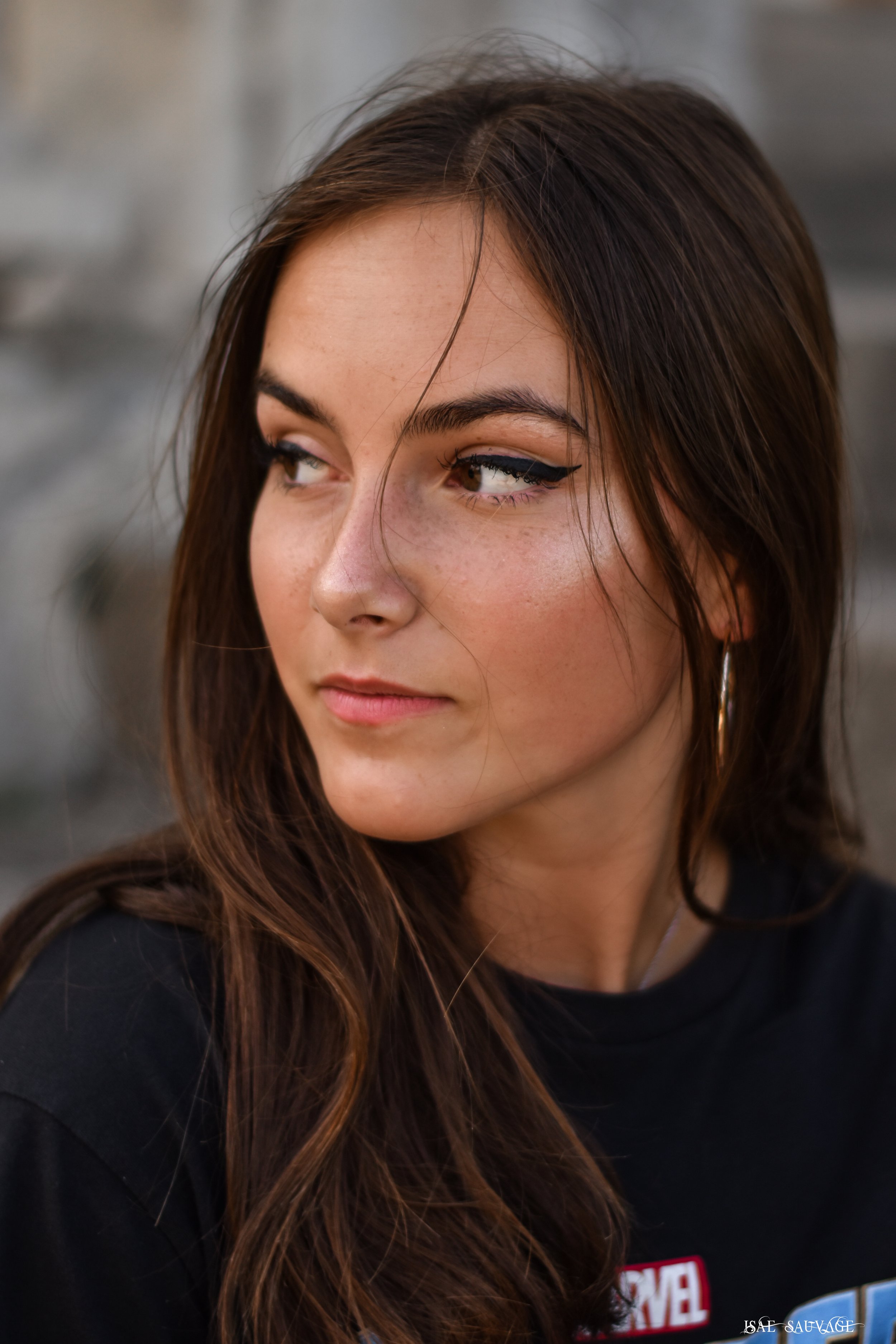 Jeune femme aux cheveux longs et bruns portant un maquillage avec un trait d'eyeliner noir et un t-shirt Marvel.