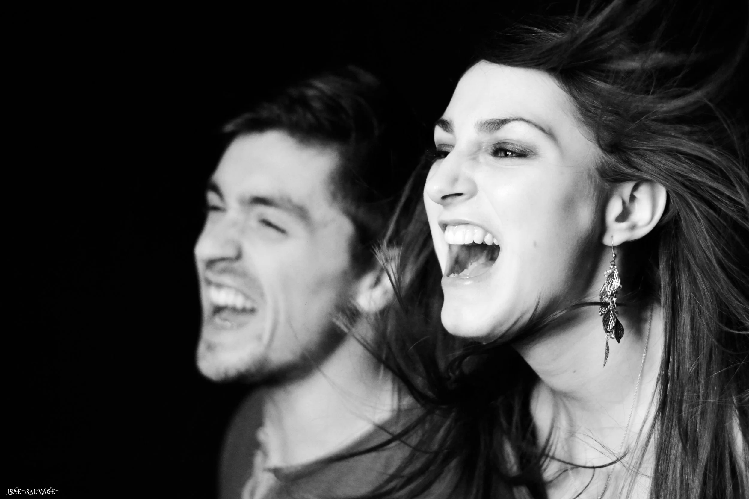 Deux personnes qui rient et sourient fortement, une femme avec boucle d'oreille en forme de feuille.