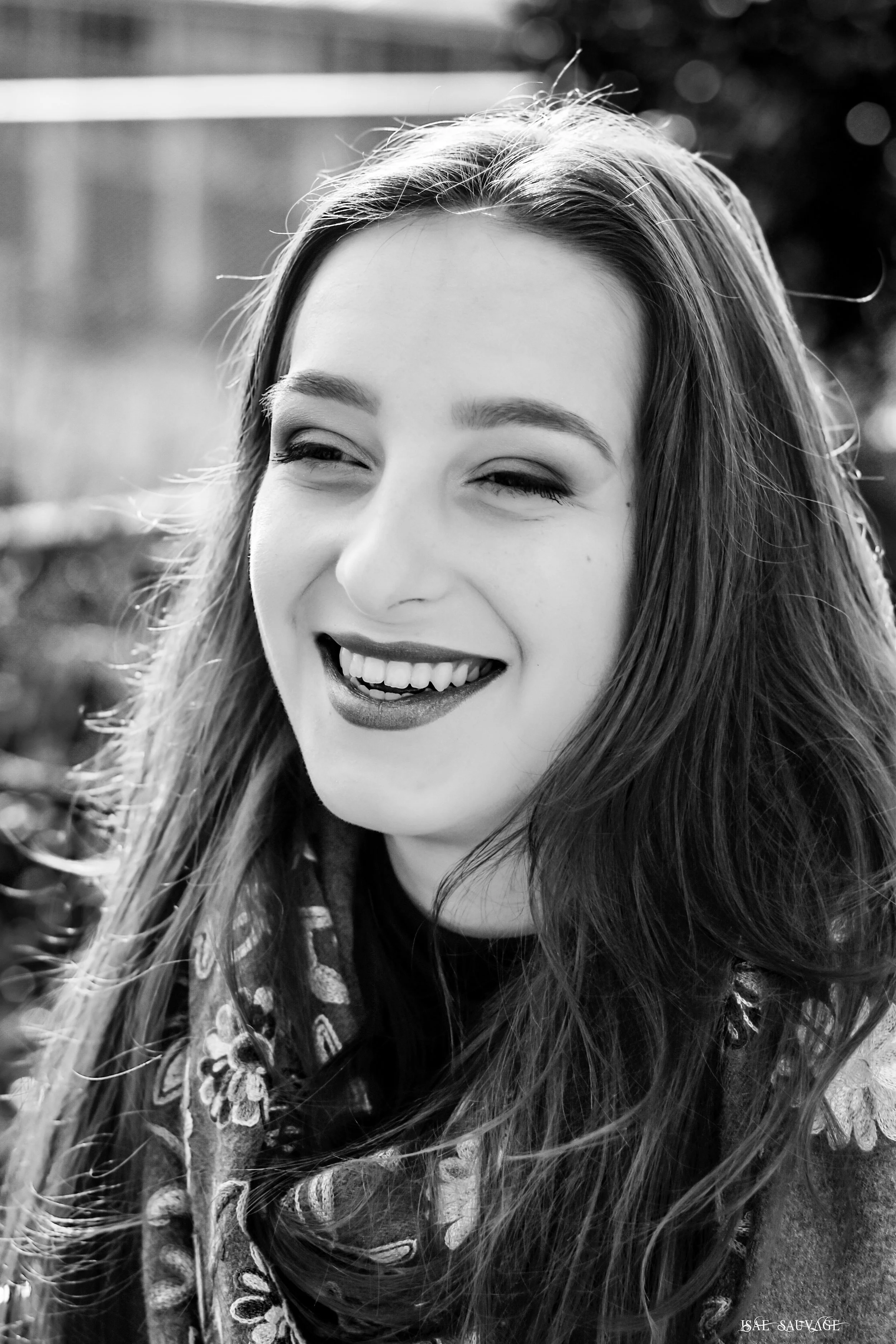 Portrait en noir et blanc d'une femme souriante avec long cheveux, portant un foulard à motifs floraux.