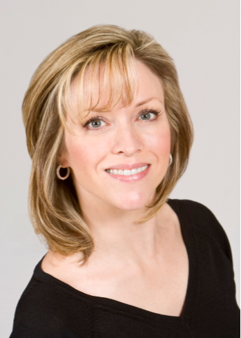 Photo of Christine Barton, blonde fair skinned  slender woman wearing small hoop earrings and a black v neck shirt.