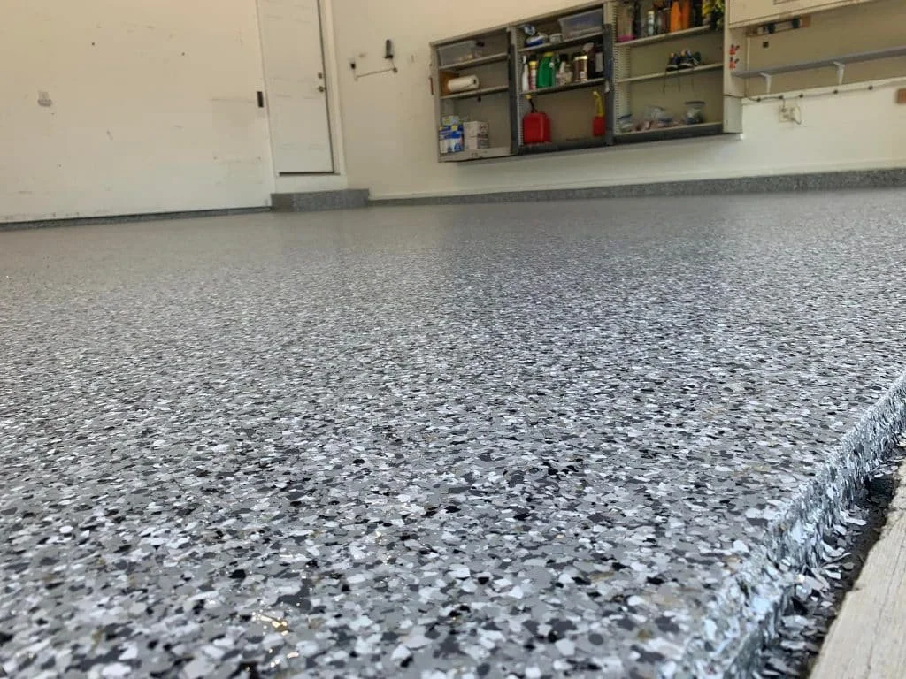 Garage floor with a terrazzo style epoxy coating and storage shelves in the background.
