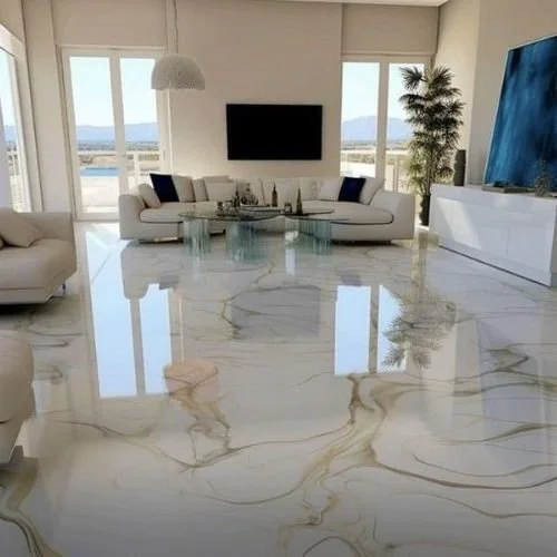 Modern living room with white marble epoxy floor, white sofa, glass coffee table, large flat-screen TV, sliding glass doors, and a tall potted plant.
