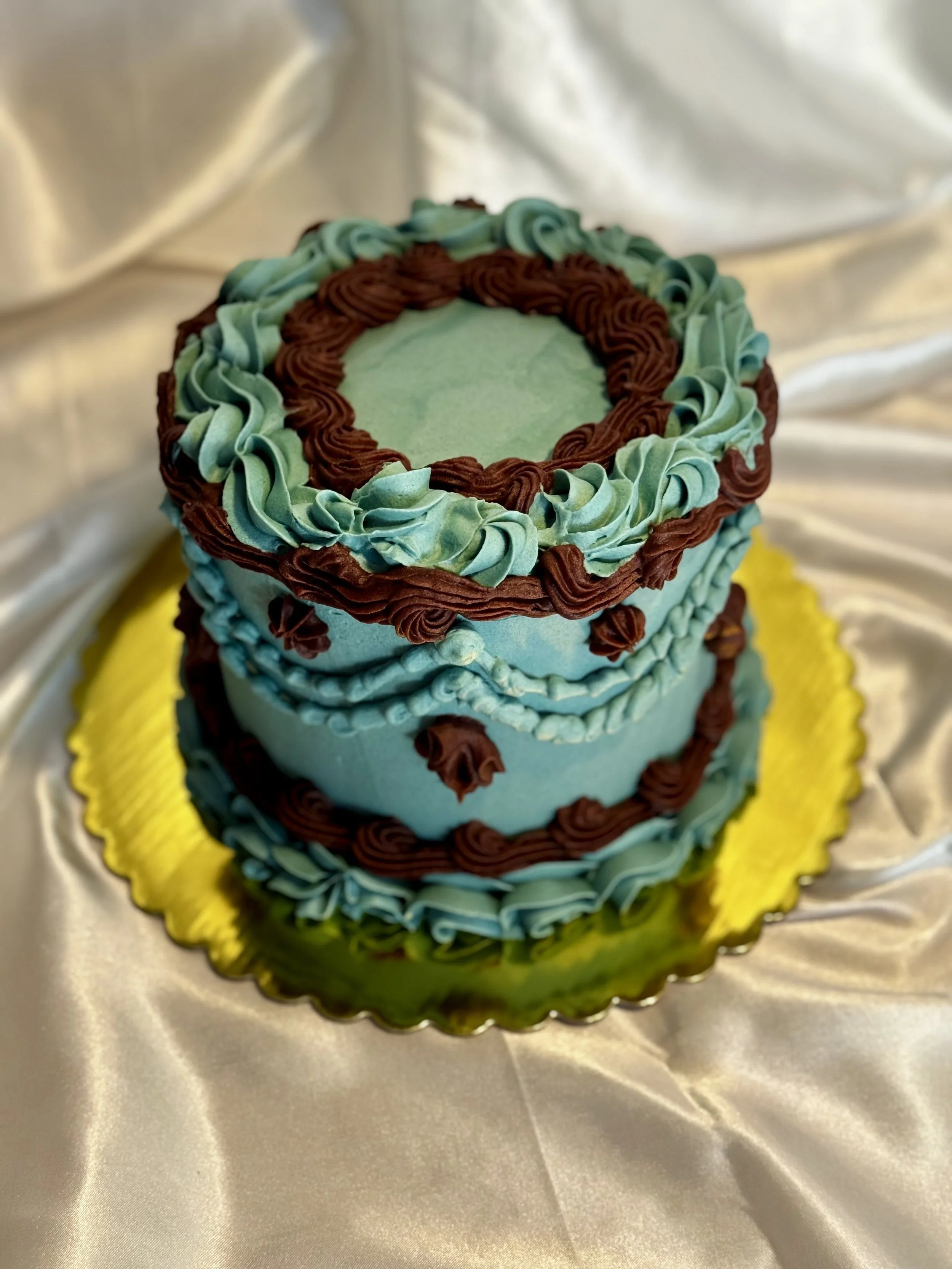 Two-tiered cake decorated with blue and brown icing, vintage style cake. 