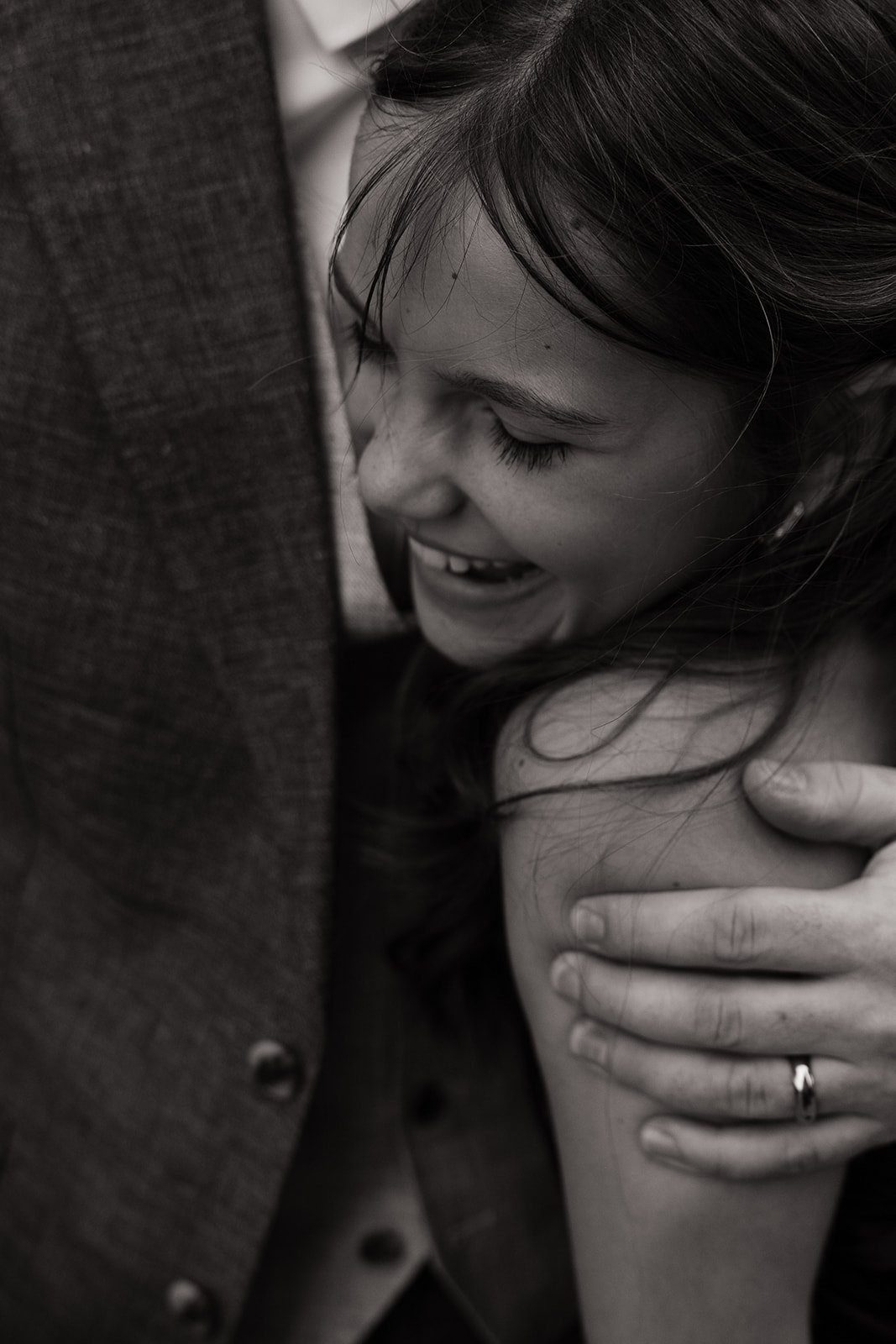 A woman smiling and leaning close to a person wearing a suit, with her hand on her shoulder, in black and white.