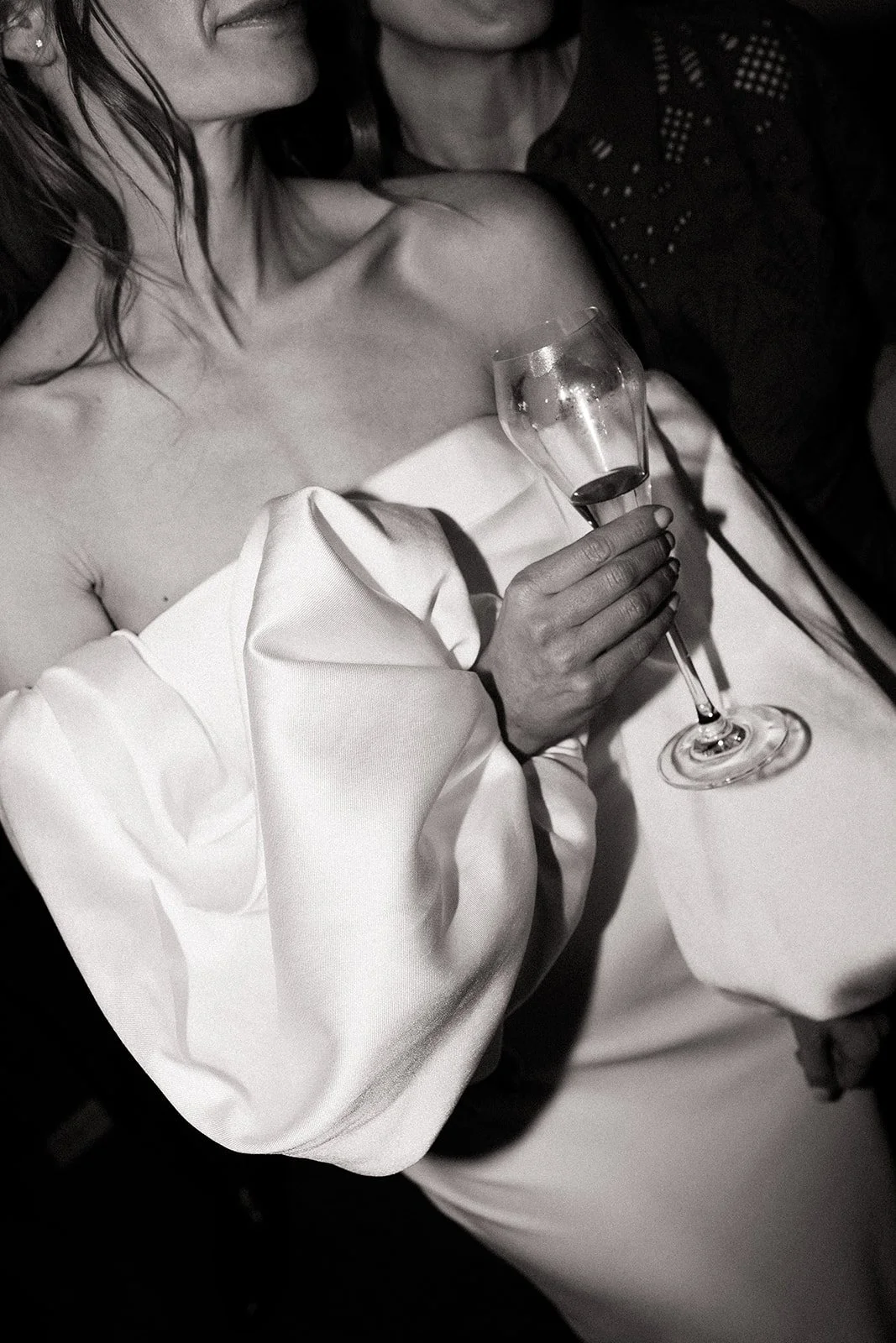 Woman in elegant attire holding a glass of wine at a formal event.