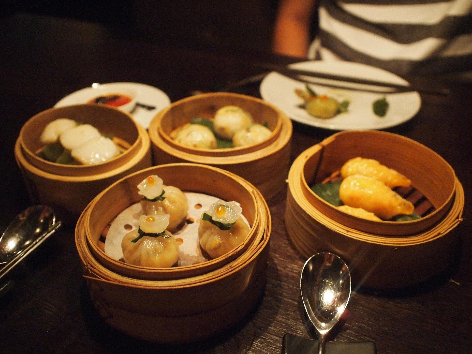 Assorted dim sum dishes served in bamboo steamers on a dark table.