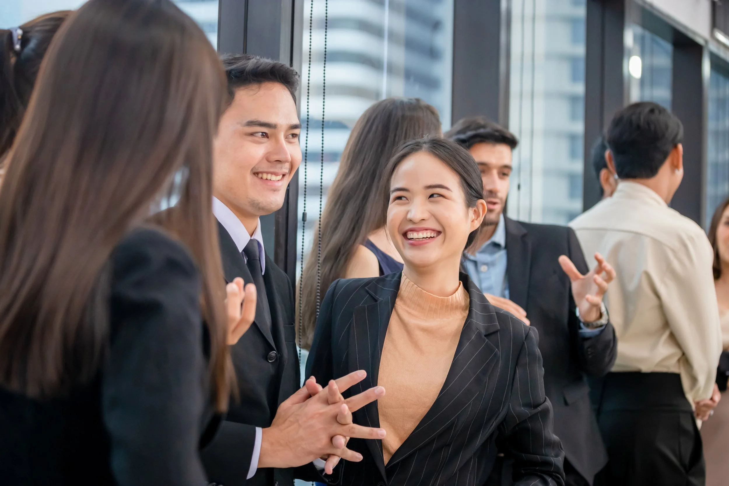 Group of diverse professionals talking and smiling in a modern office building