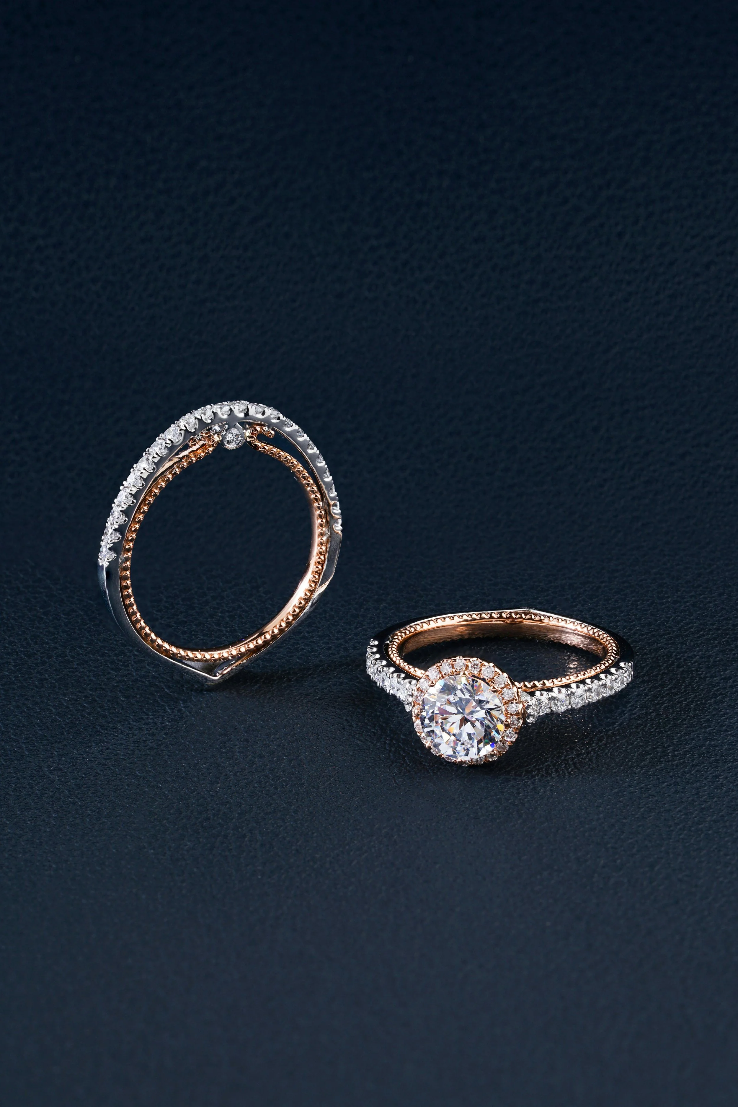 Two elegant rings with diamonds on a dark textured background.