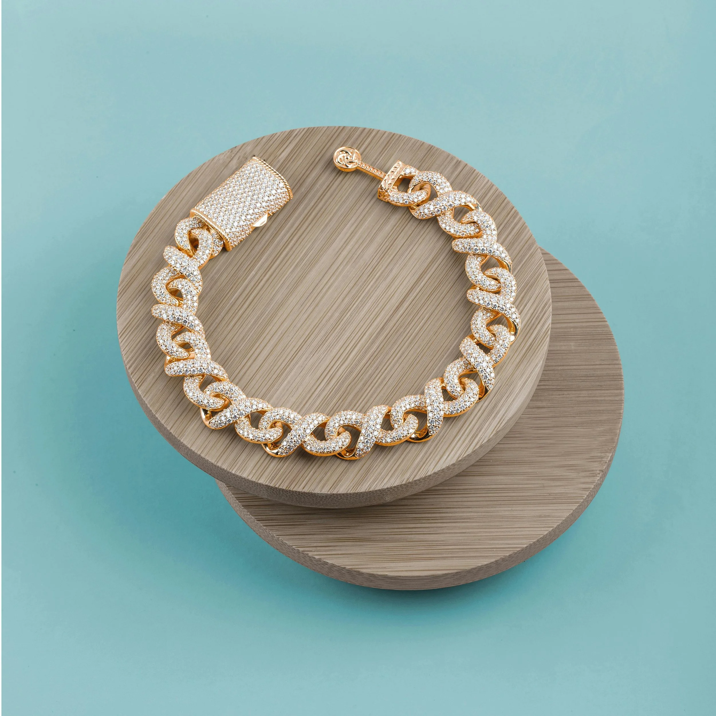 Gold chain necklace encrusted with diamonds worn on a beige wooden platform.