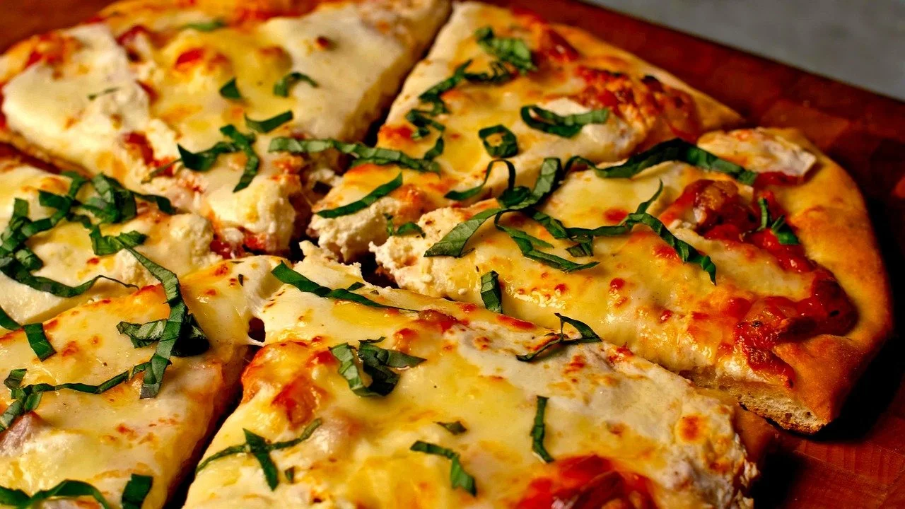 Close-up of a cheese pizza topped with chopped basil.