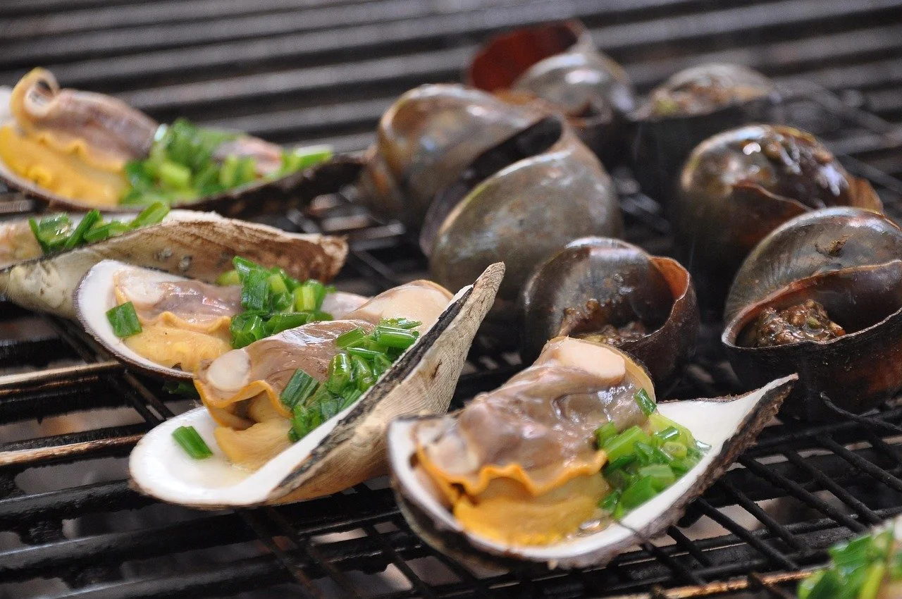 Clams on a grill topped with chopped green onions.