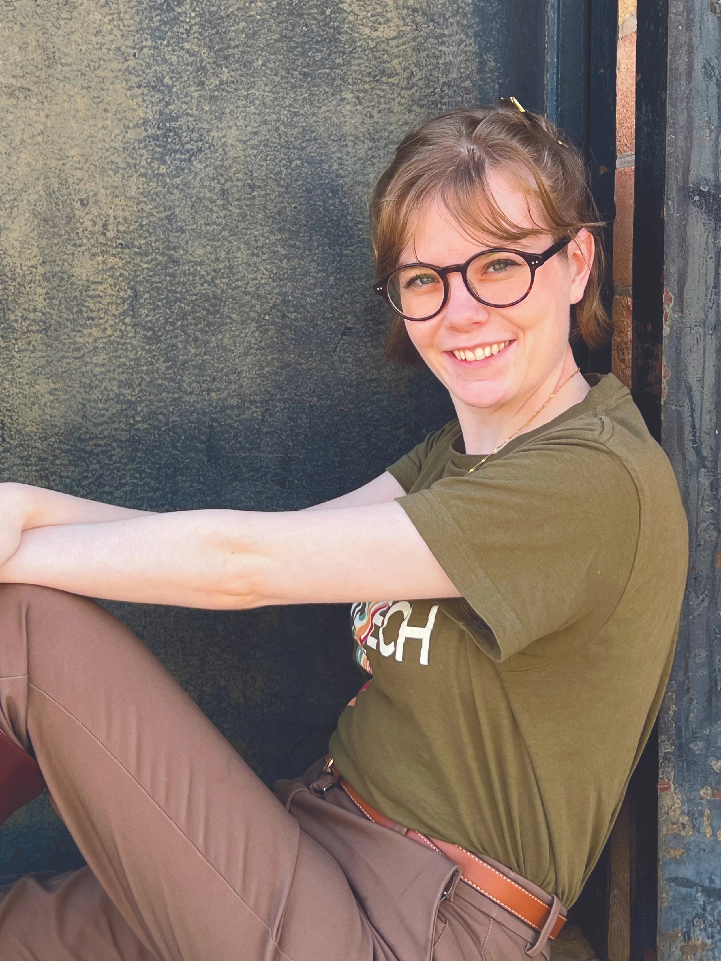 Sabrina leans against a door and smiles.