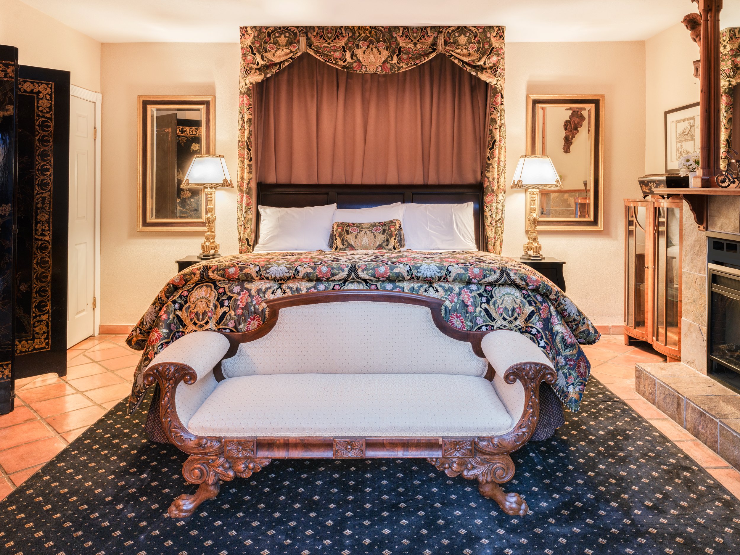 An elegant bench sits at the foot of the king-size bed in the bedroom of the private cottage.