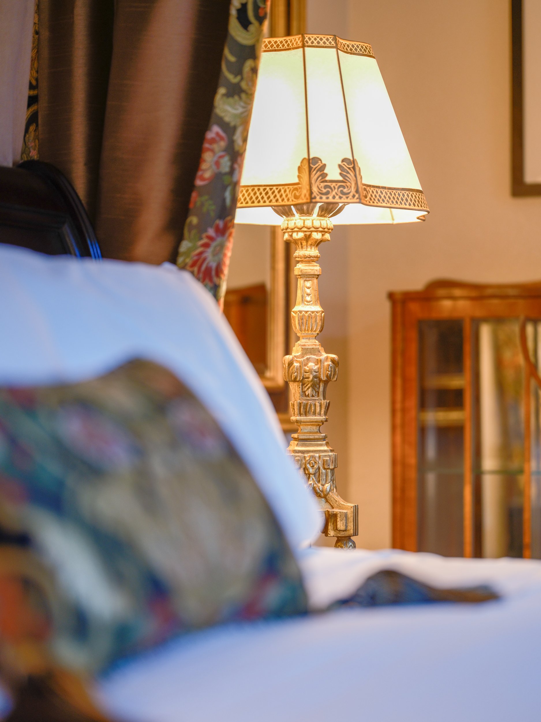 An ornate, golden bedside lamp sits next to the draped headboard in the private cottage.