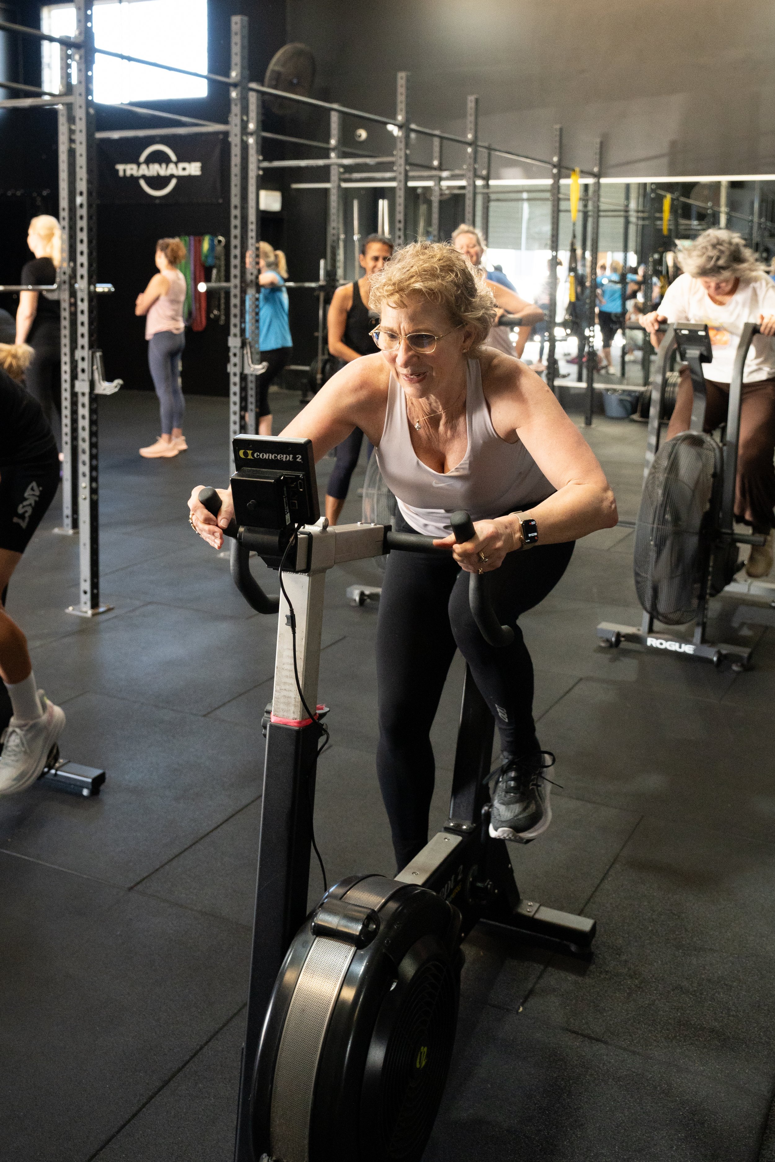 Middle aged woman cycling on stationary bike in group menopause exercise class on the Gold Coast