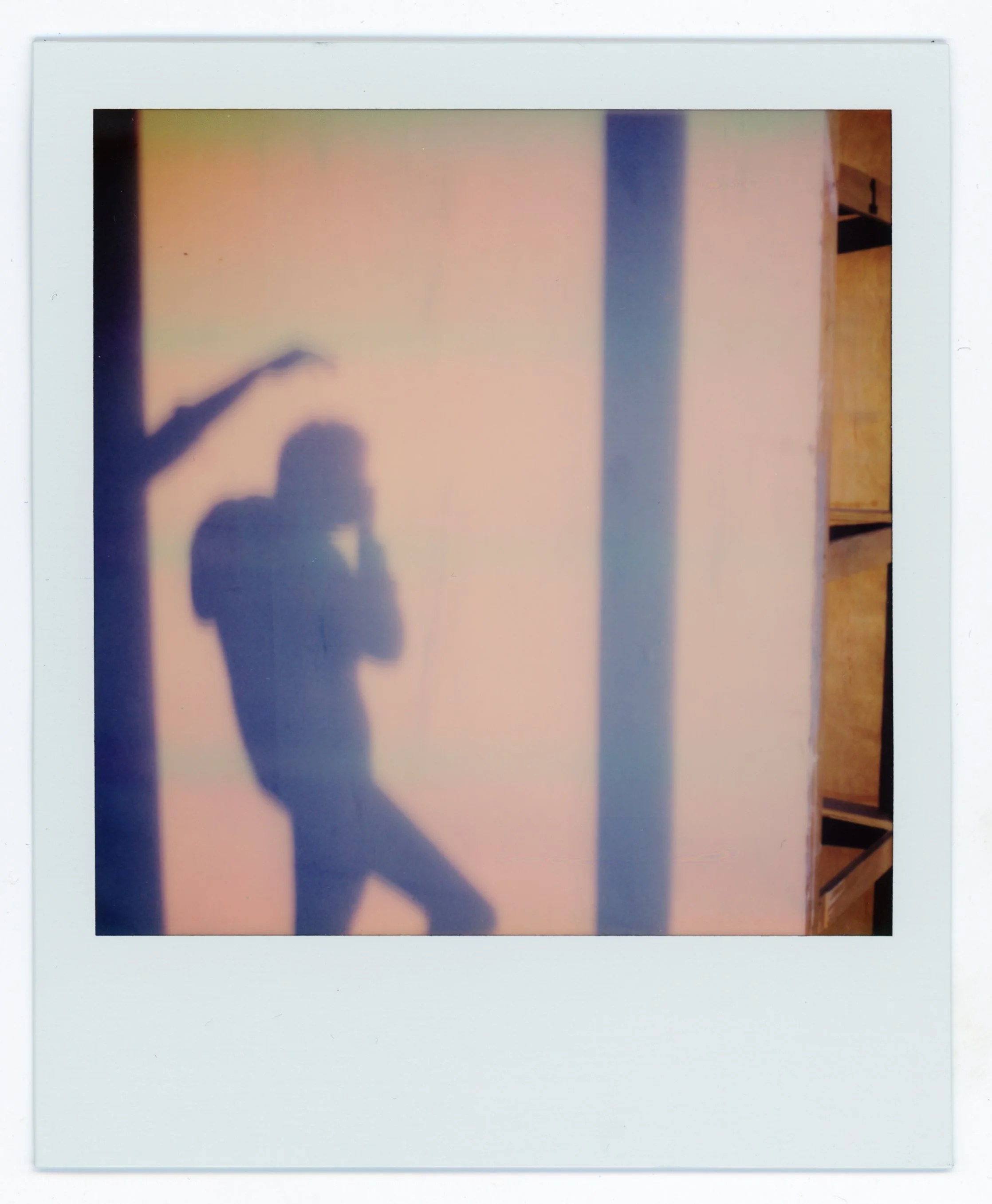 The shadow of a person taking a photo on a smooth, reflective surface with a colorful, gradient background.