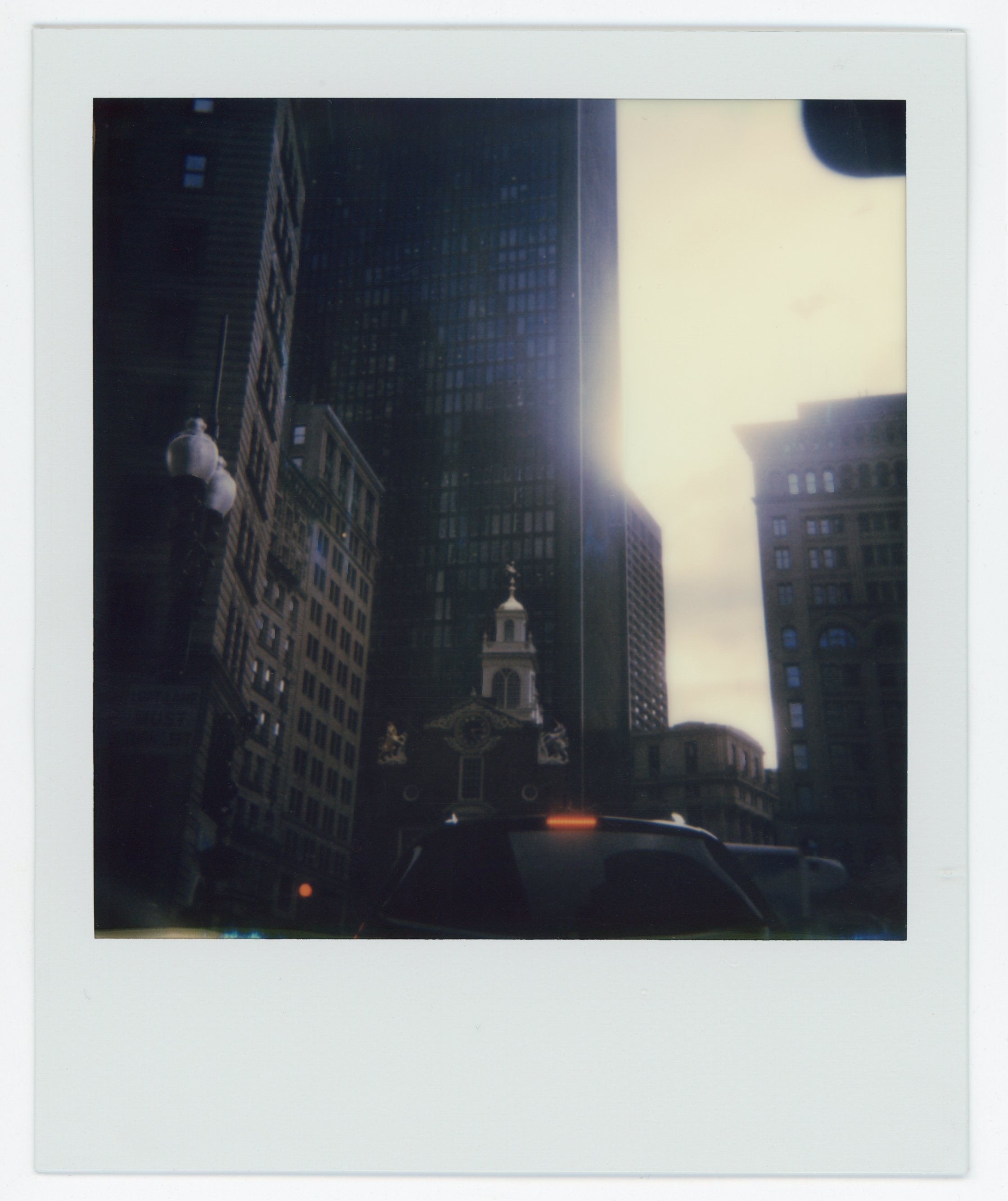 Reflection of tall buildings and a church steeple in a glass window on a city street in daylight