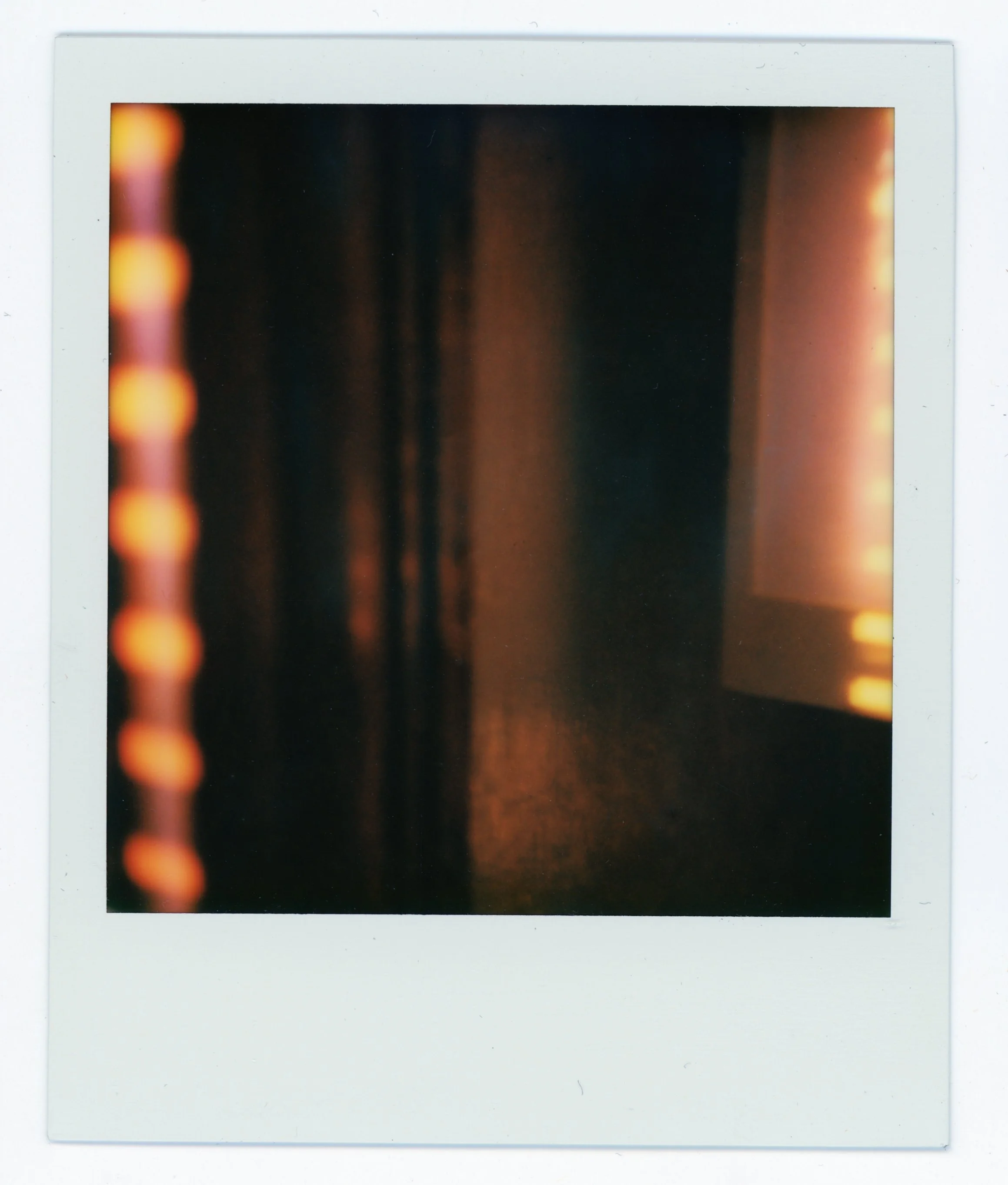 Blurred dark interior scene with warm lighting and vertical lines.