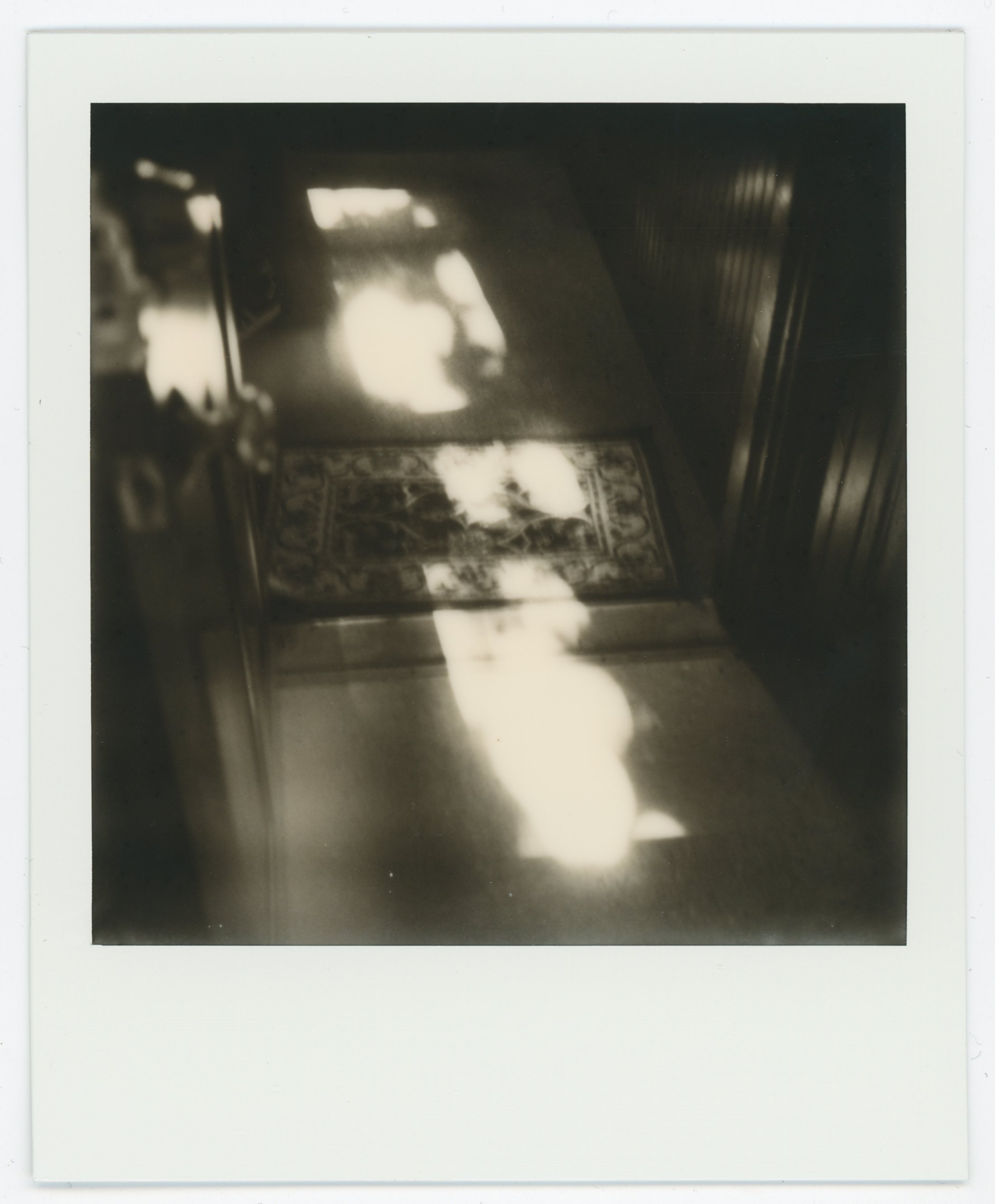 Sunlight casting abstract patterns on a wooden table with a decorative tile centerpiece, surrounded by wooden furniture.