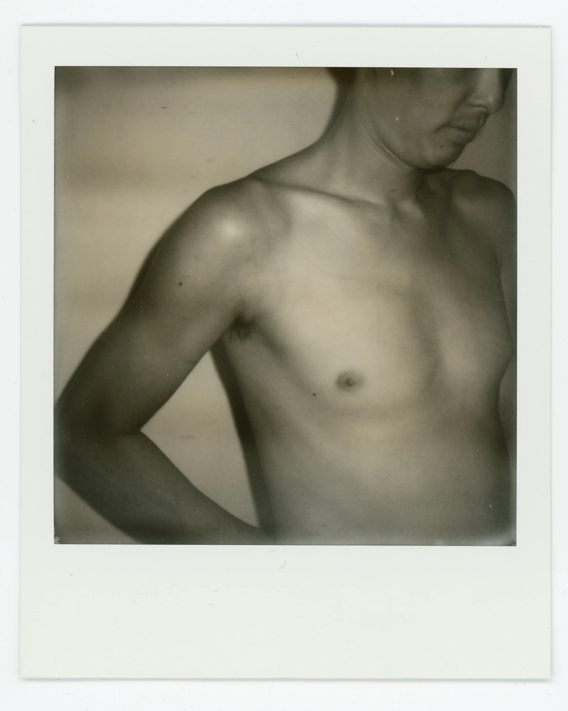 Black and white photograph of a shirtless man shown from the chest up, with his head turned to the side and face partially visible.