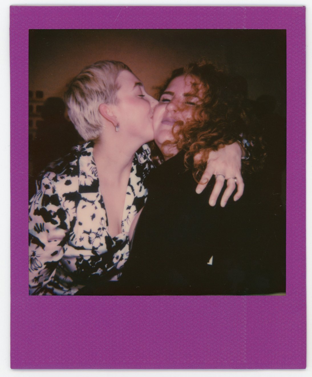 Two women hugging and smiling, one giving a kiss on the cheek to the other.