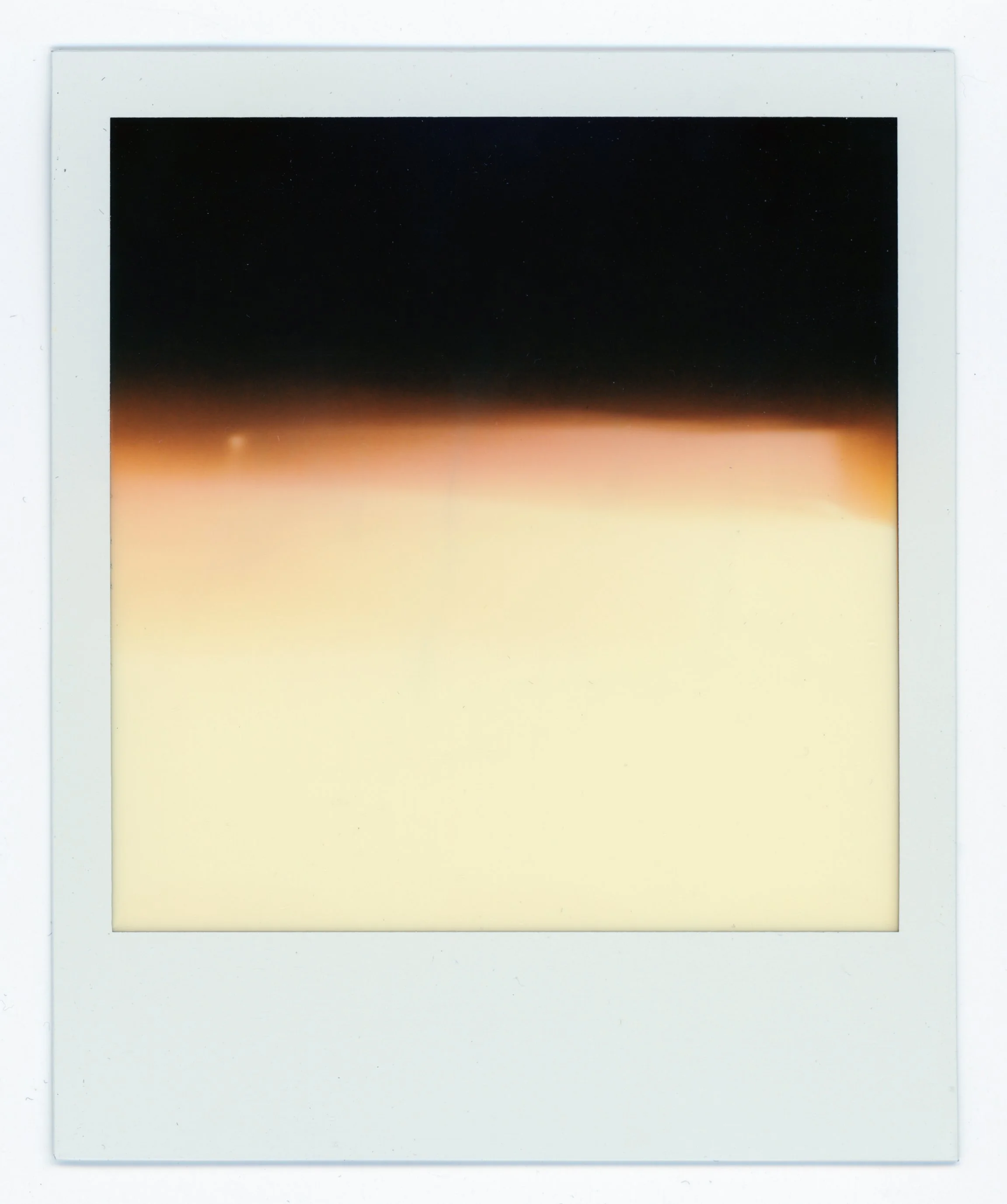 Polaroid photo showing a gradient sunset sky transitioning from dark at the top to light at the bottom.