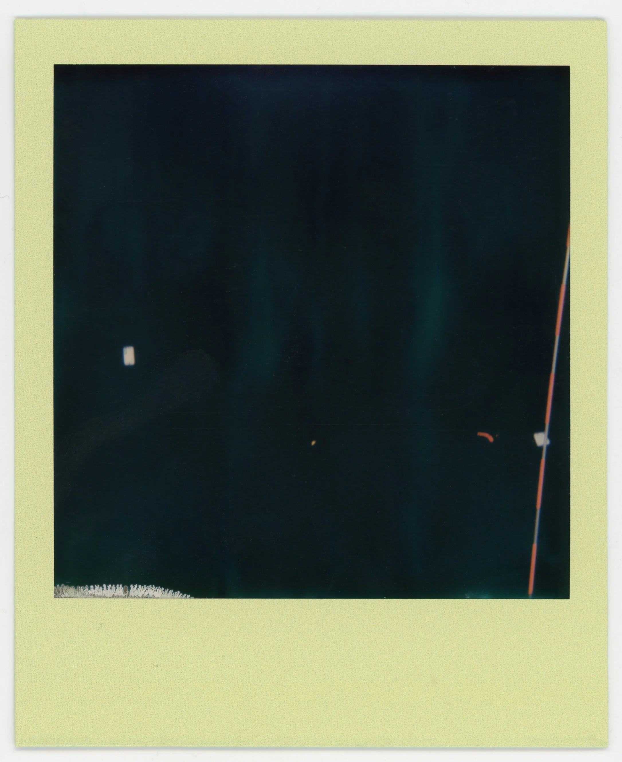 A Polaroid photo with a faded, dark image and a skin-tone colored border.