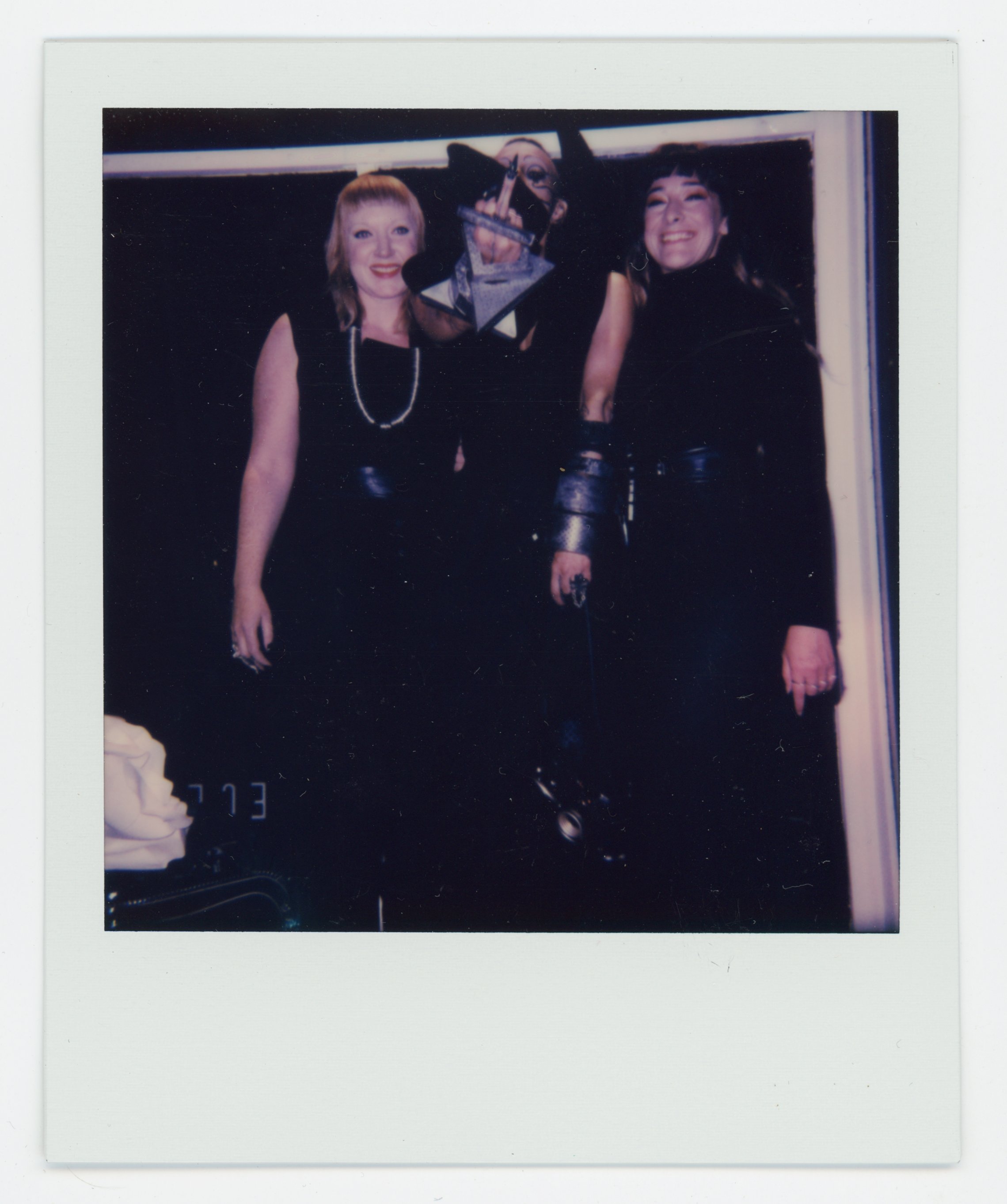 Three women dressed in black posing for a photo at an event, with one holding a trophy shaped like a star.