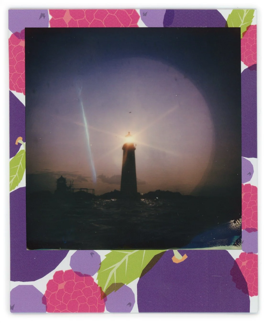 Lighthouse on a rocky shore at night with the lighthouse's light shining and a bright halo effect around it.