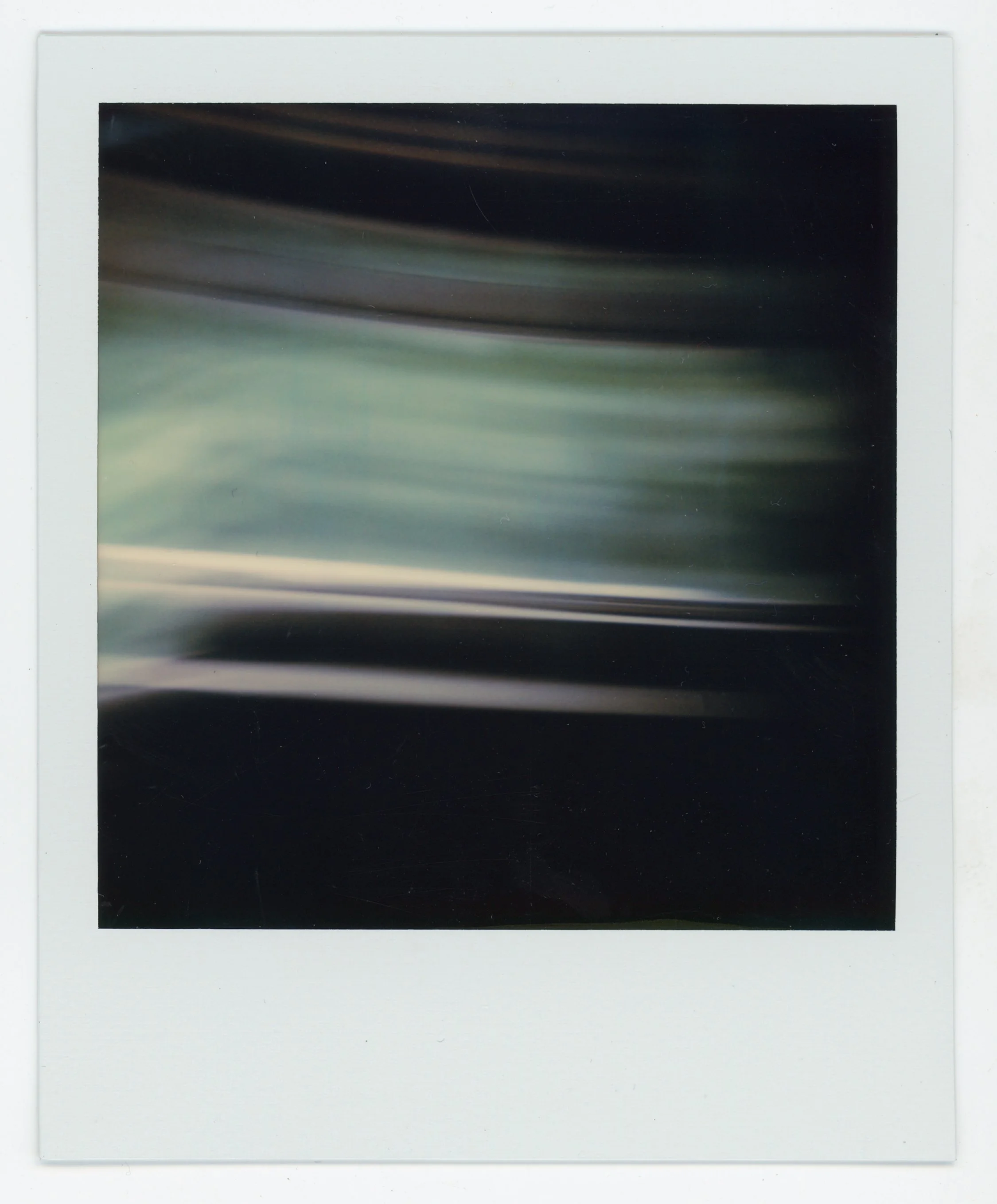 Abstract blurred photo with streaks of green, white, and black.