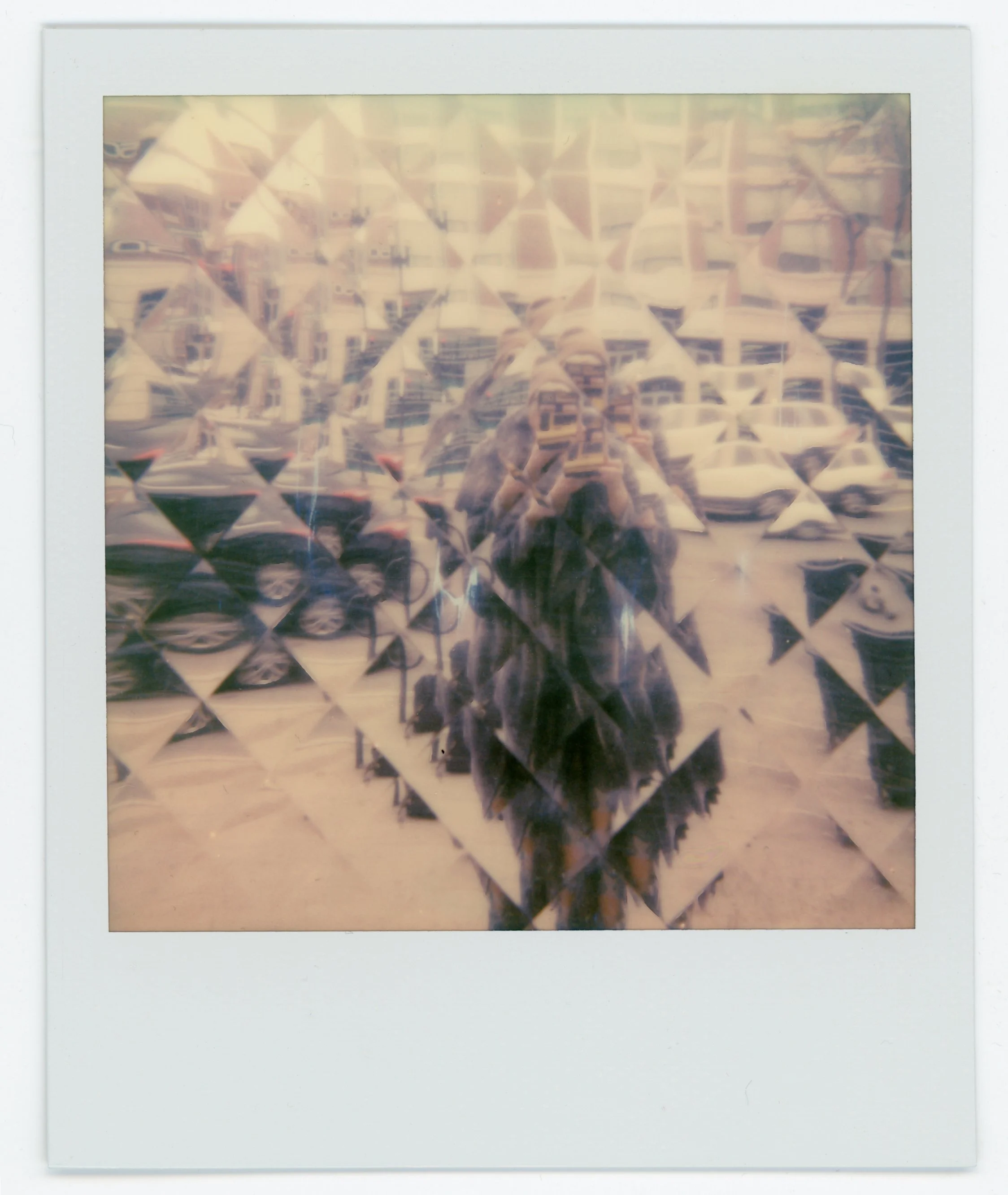 Reflection of a person taking a photo on a decorative glass display with a background of parked cars on the street.