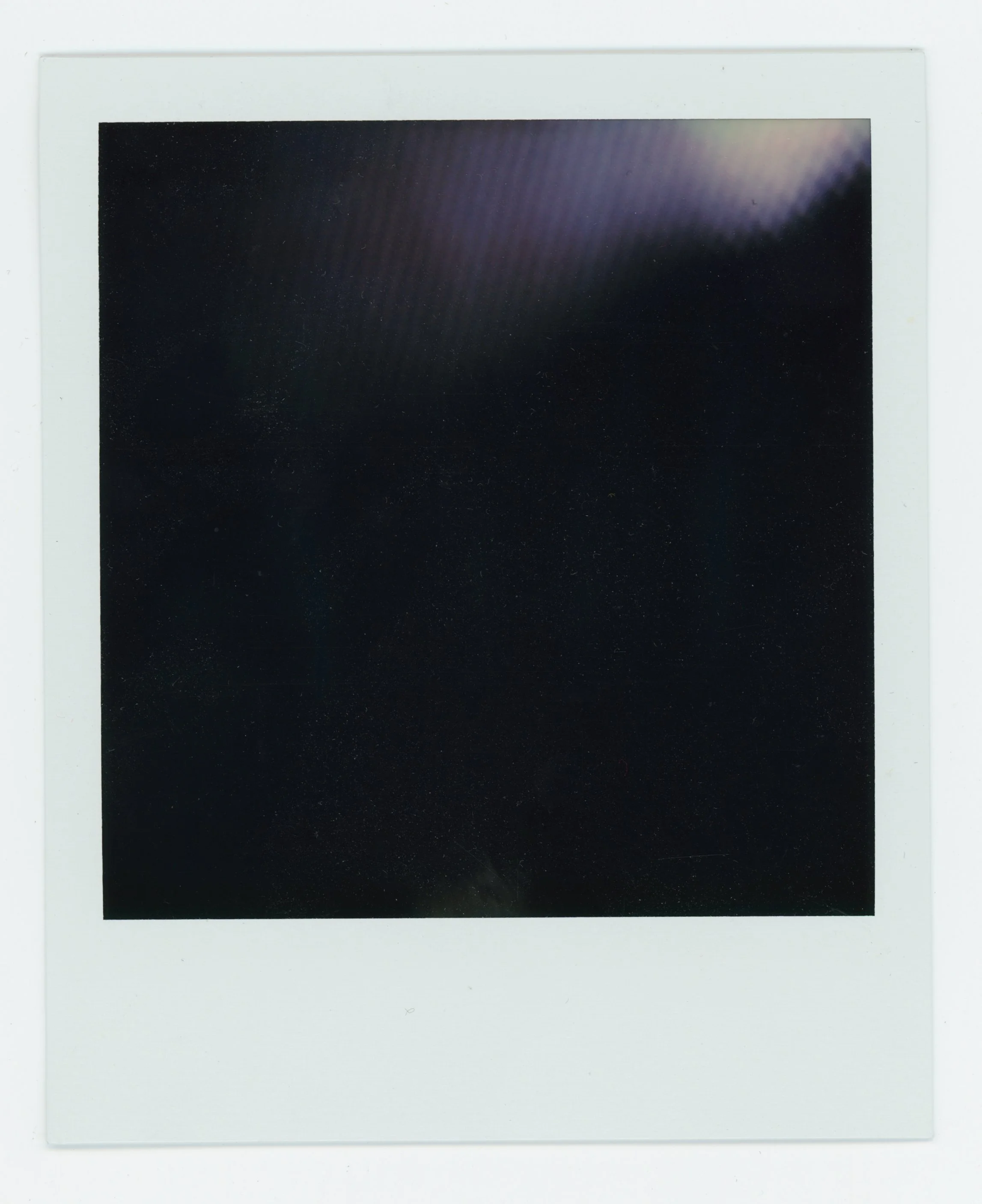 A blank white Polaroid photo with a black square in the center.