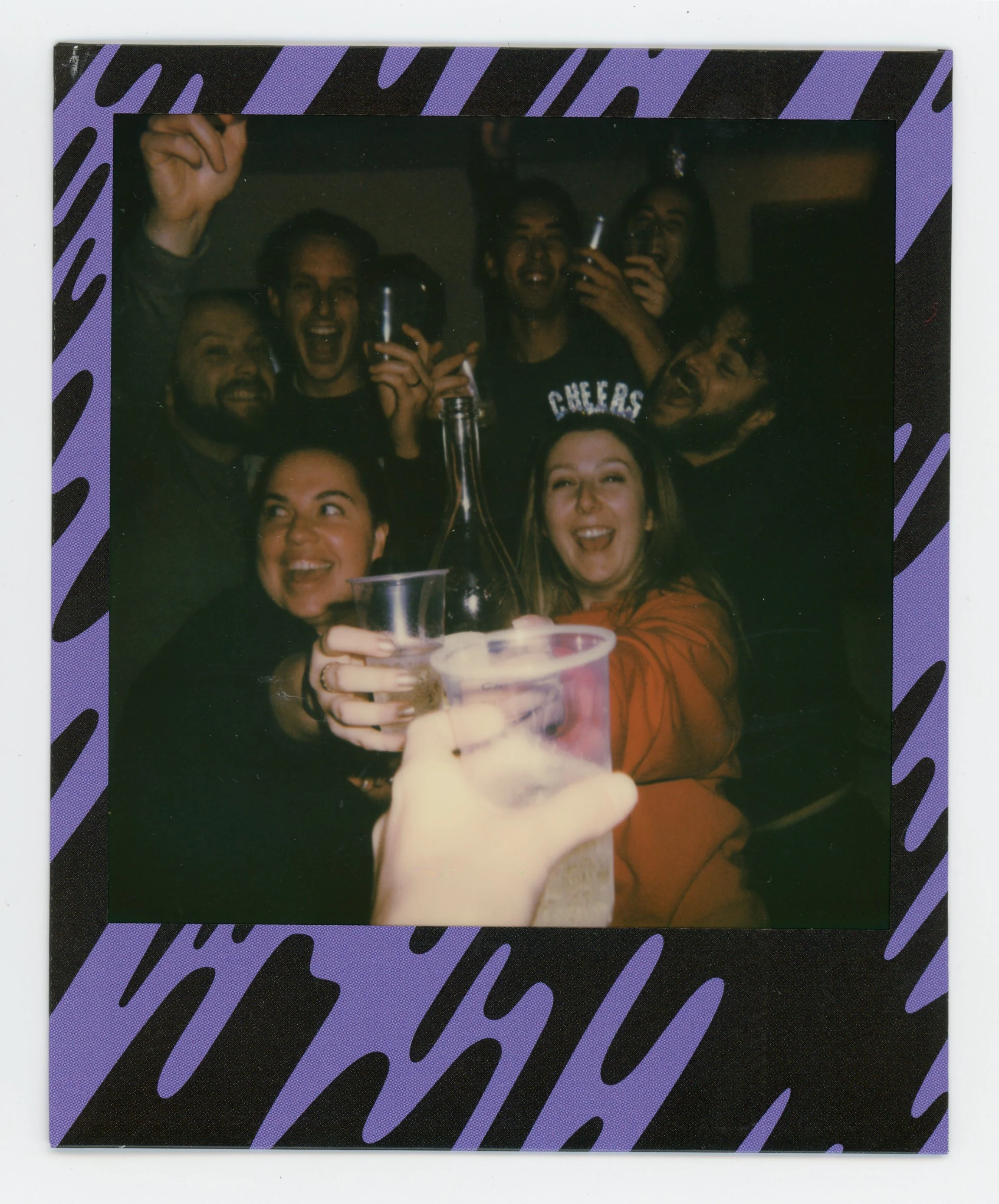 Group of friends celebrating with drinks at a party, raising glasses and smiling together.