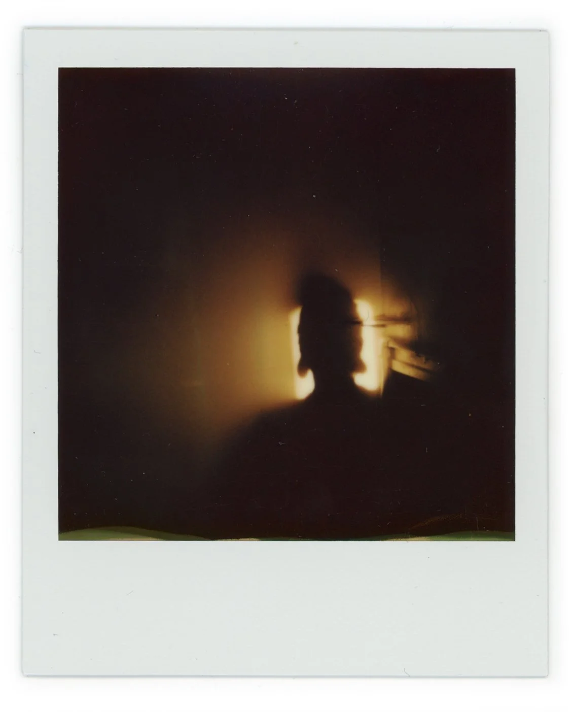 A silhouette of a person with a light source behind them creates a glowing outline on the wall, with the person's head and shoulders visible.