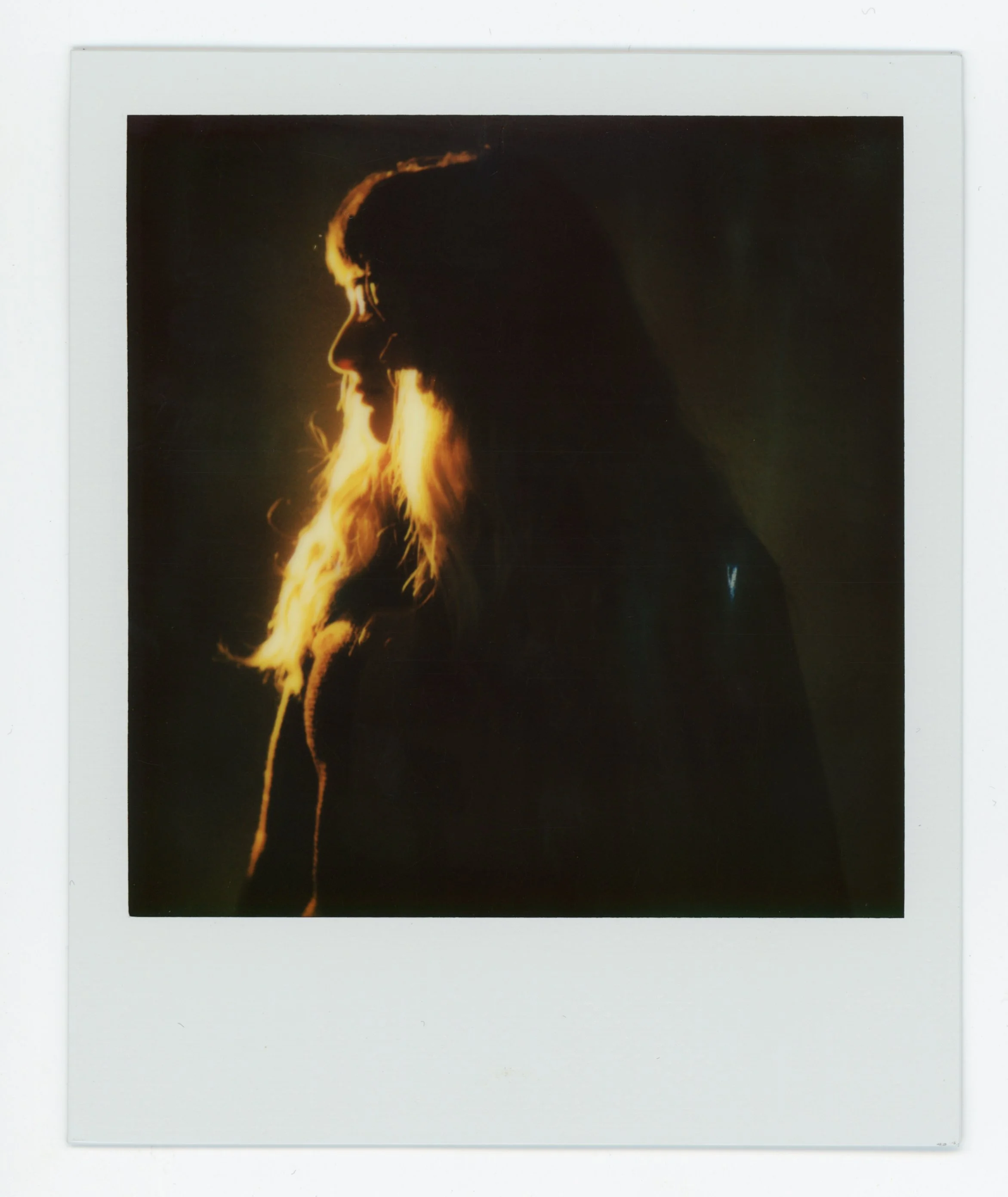 Silhouette of a woman with long hair, backlit with warm light, creating a glow around her profile.