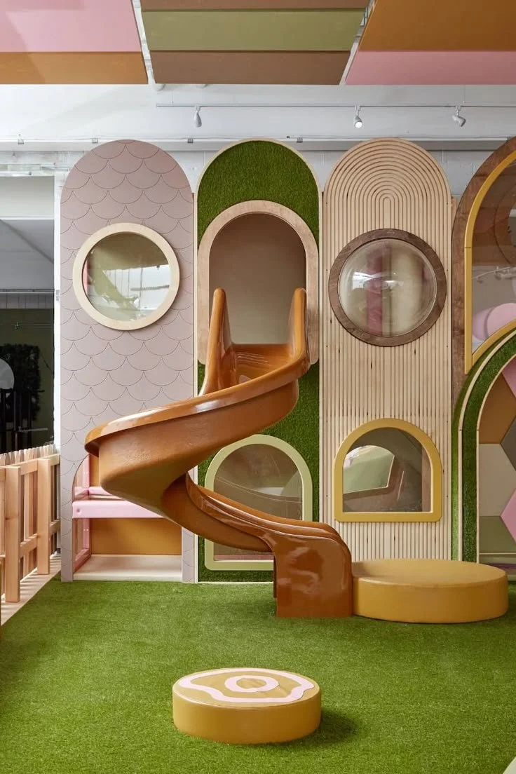Colourful indoor play area with a faux grass floor and a spiral fibreglass slide for Tigerplay. Creative and Custom fibreglass and composite solutions.