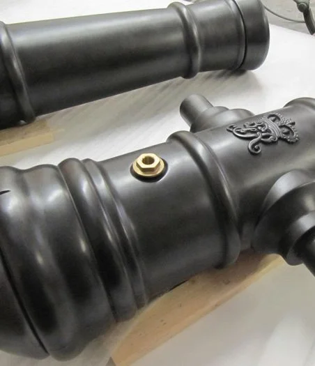 Close-up of a black antique cannon with decorative details and a small gold-colored bolt.  Creative and Custom fibreglass and composite solutions. 