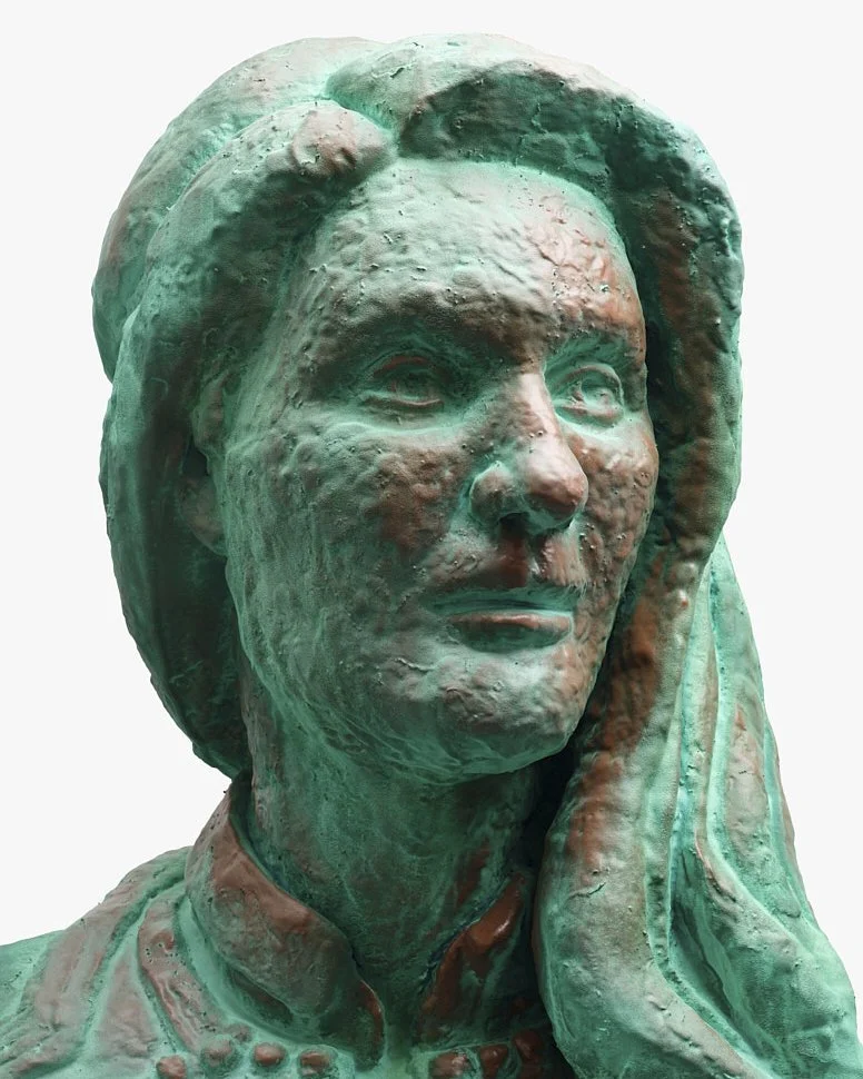 Close-up of a bronze bust sculpture of a woman with a textured surface, featuring long hair and a serious expression.