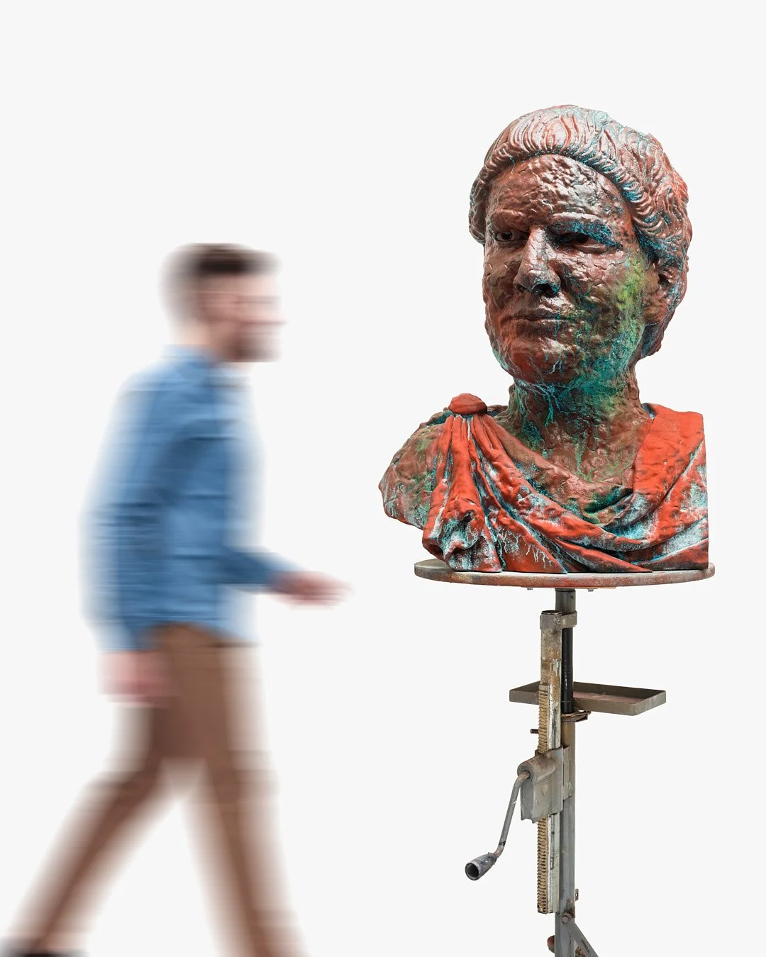 A man walking past a colorful sculpture of a woman's bust on a stand.