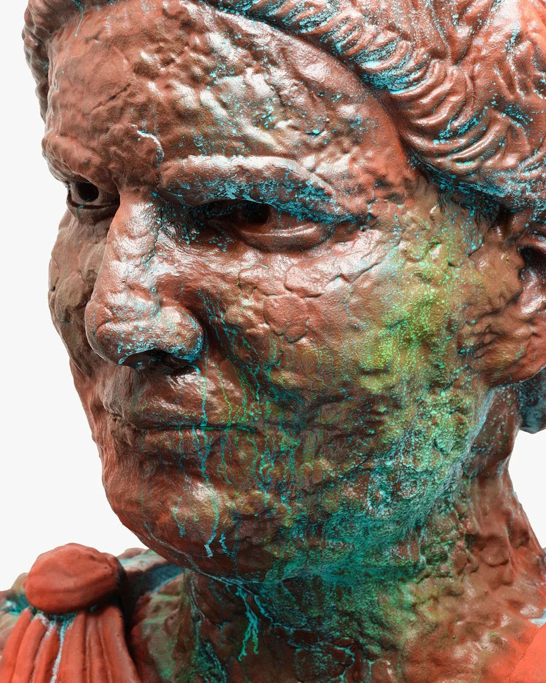 Close-up of a sculpture of a person with a weathered face, representing a historical or mythological figure, with turquoise and green paint splatters.