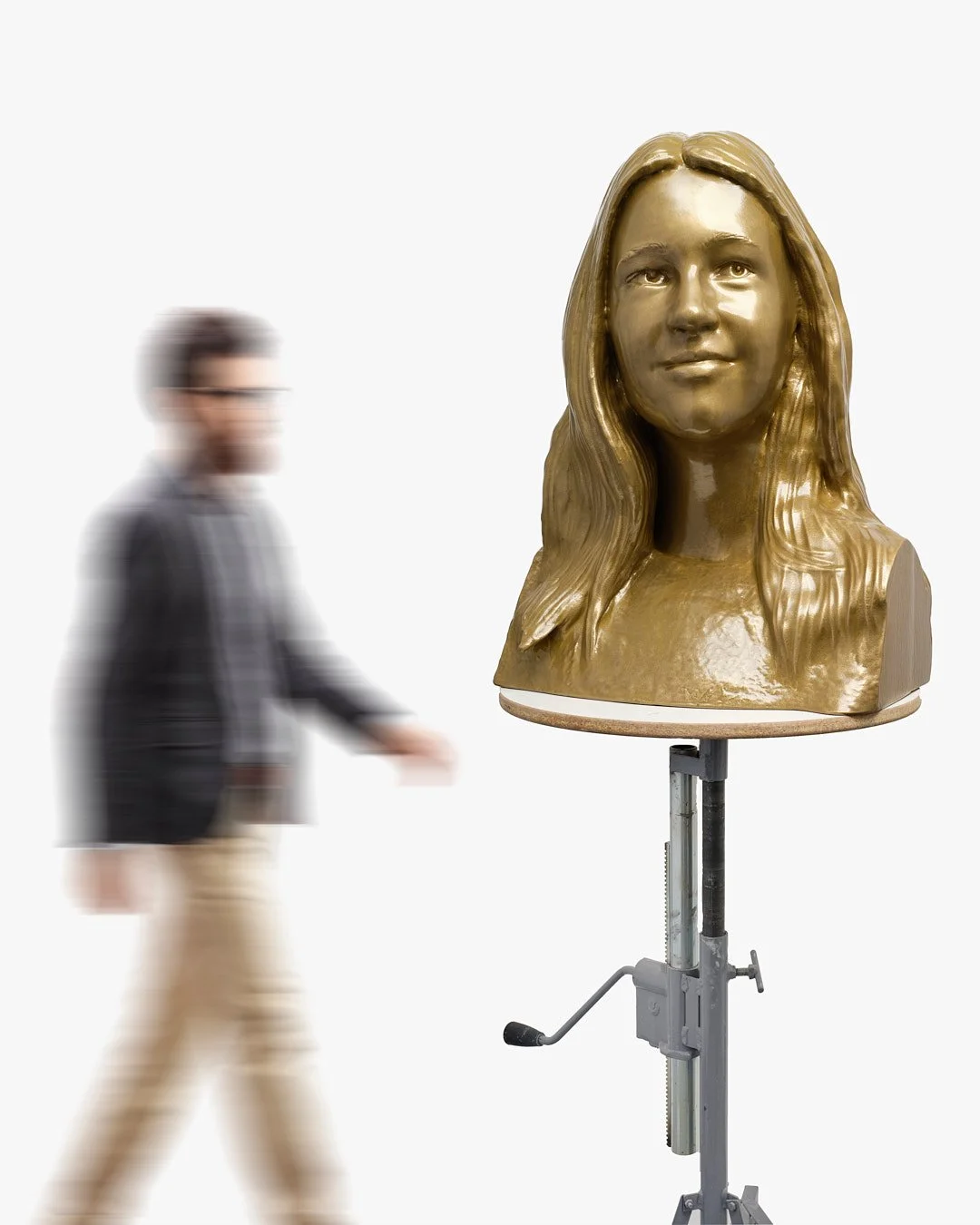 A man walking past a golden bust sculpture of a woman's head on a stand in a white, featureless background.