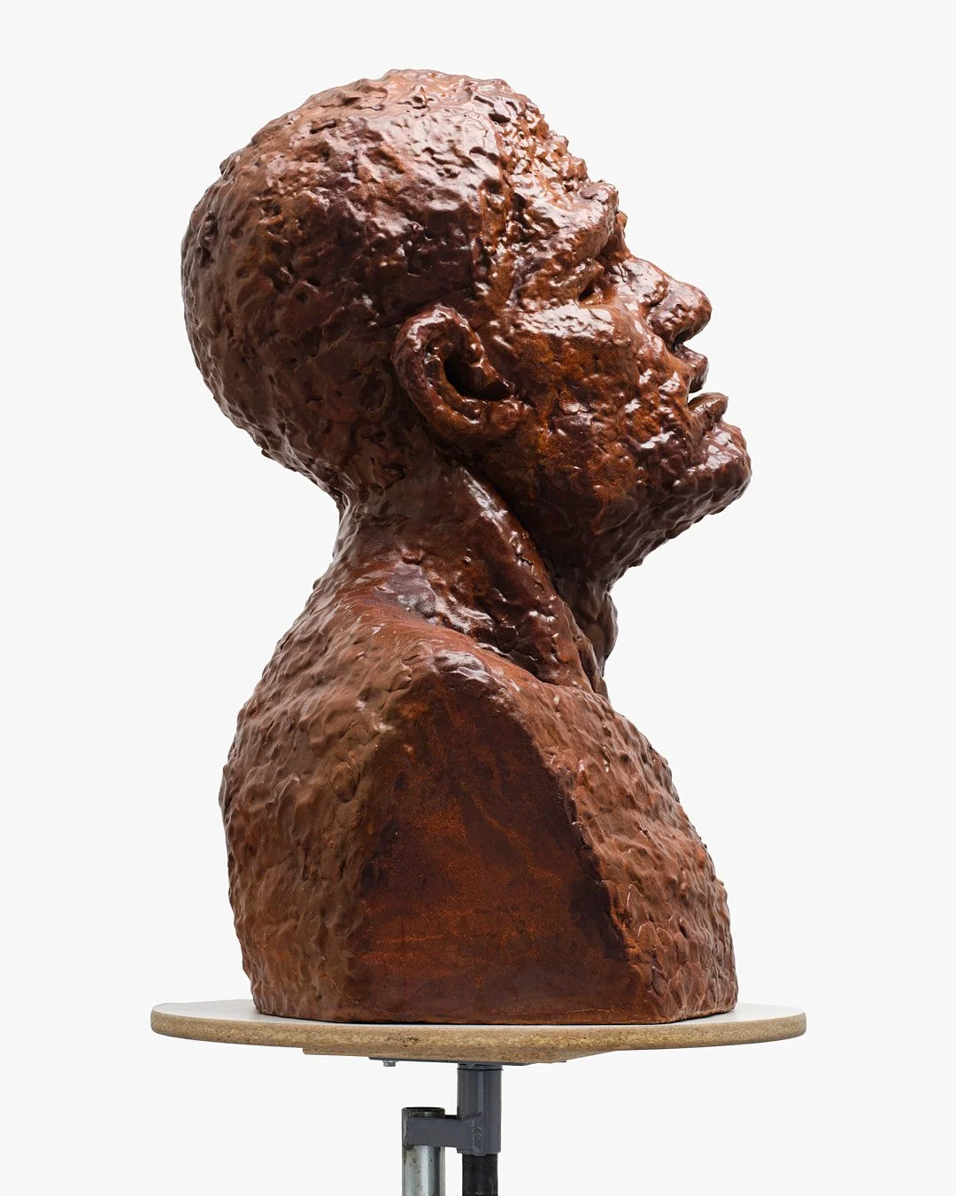 Bronze sculpture of a woman’s side profile, mounted on a wooden base.