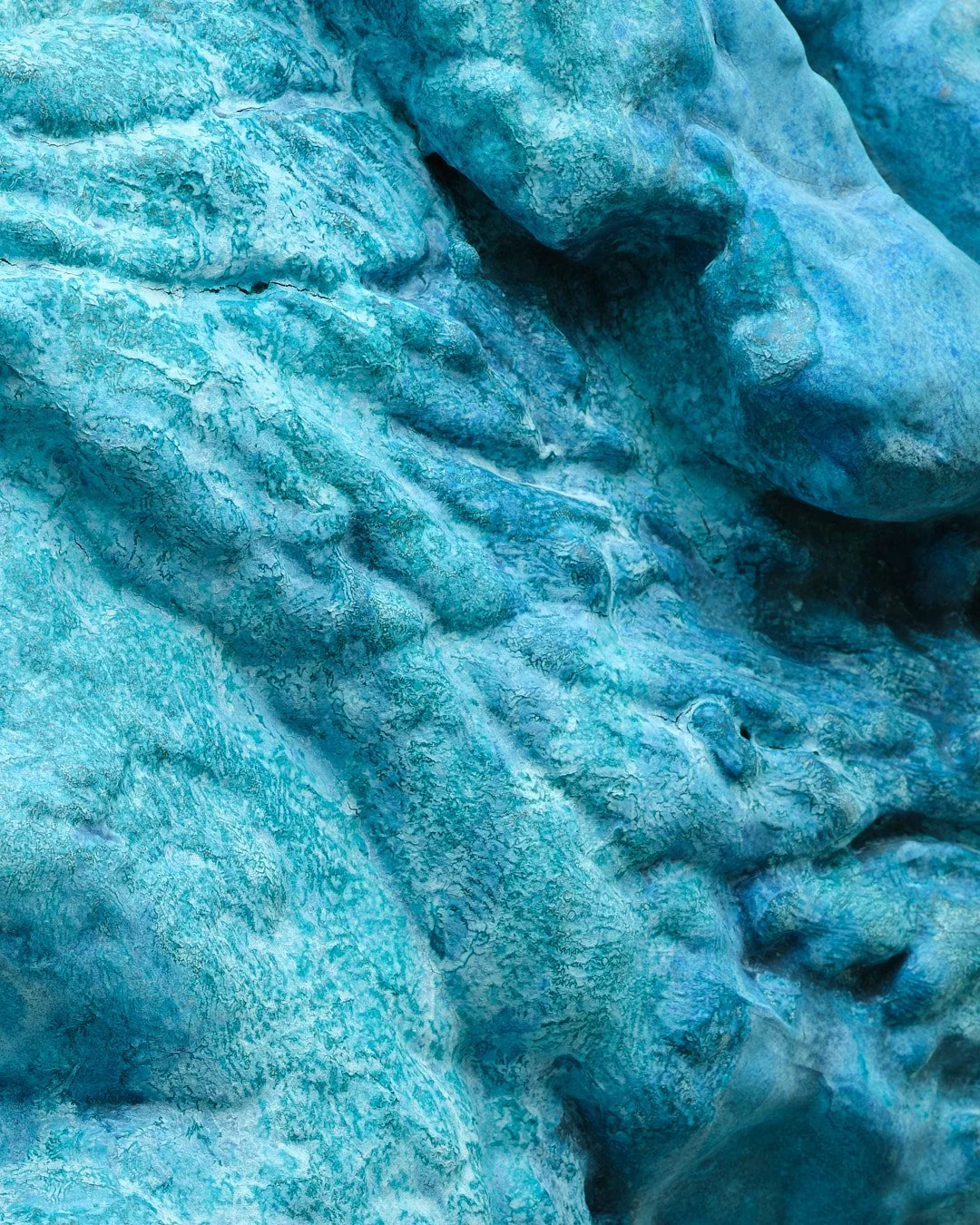 Close-up of a glacier's surface showing textured ice in shades of blue.