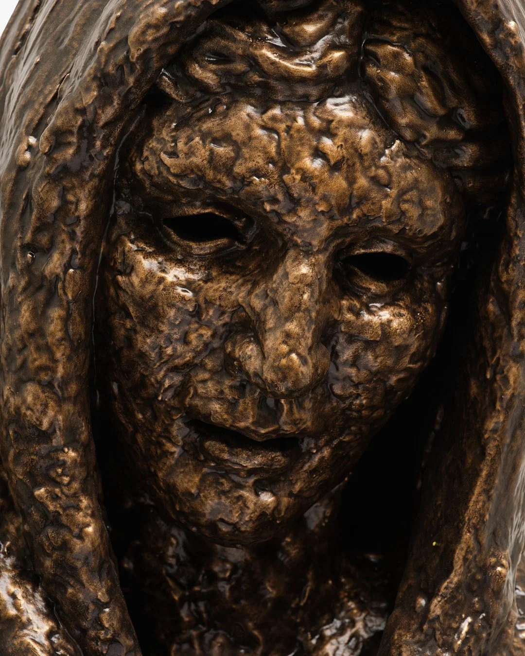 Close-up of a bronze sculpture of a woman with a distressed expression, holding her head with both hands.