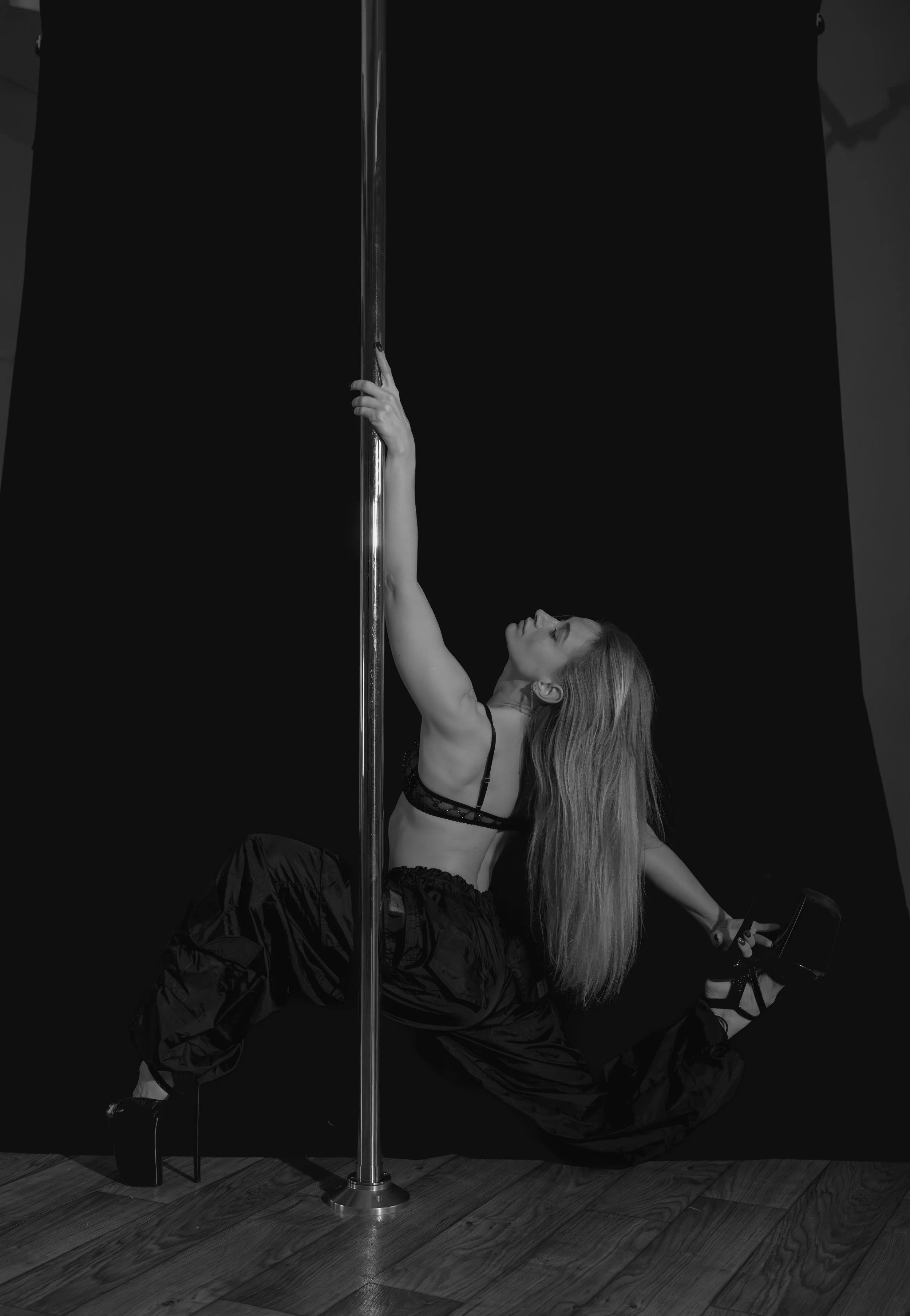 Een vrouw aan een paal met paaldansen of pole dance die danst en gymt.